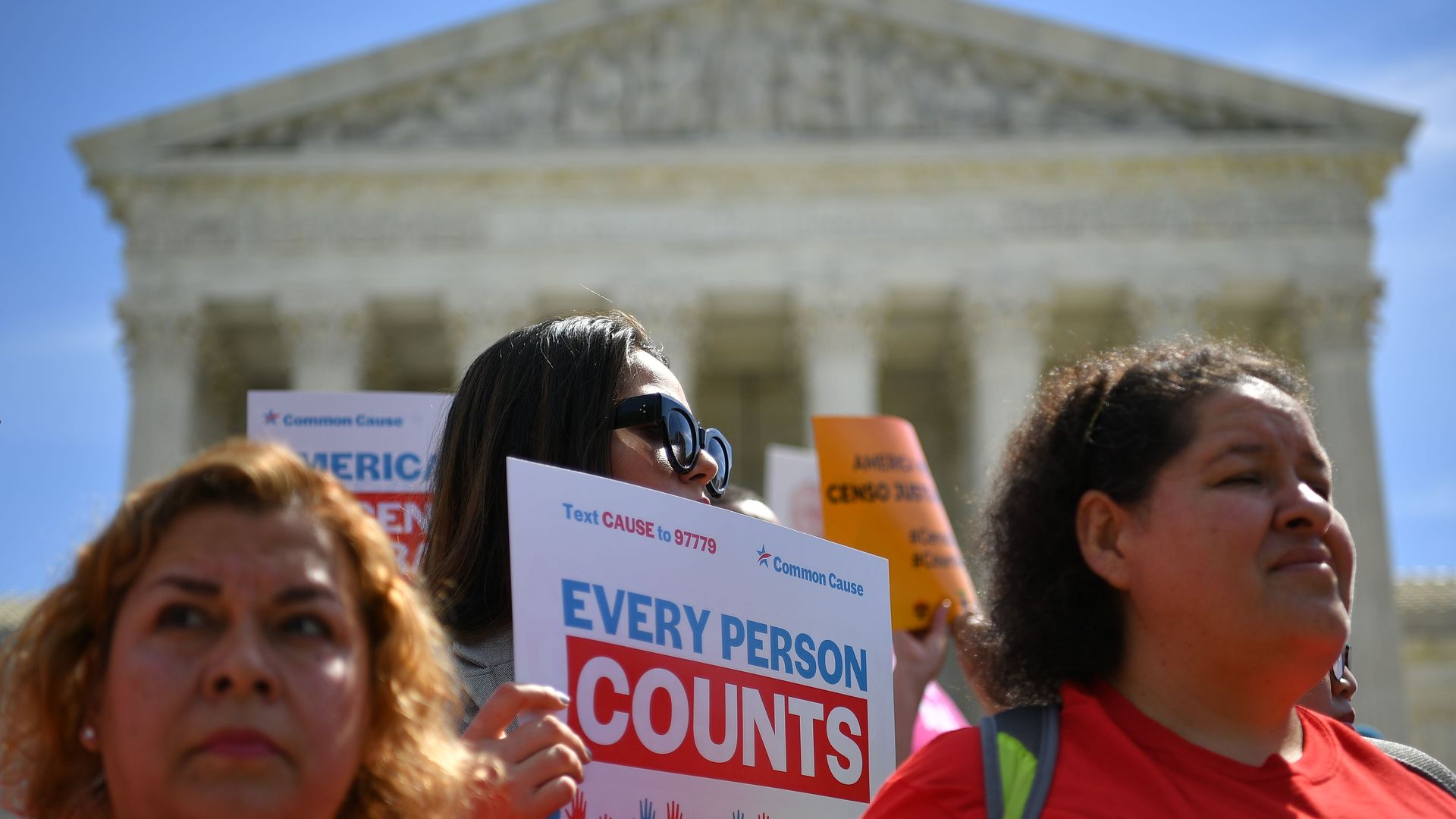 Protesters wave signs that say "Every person counts" in front of the Supreme Court building