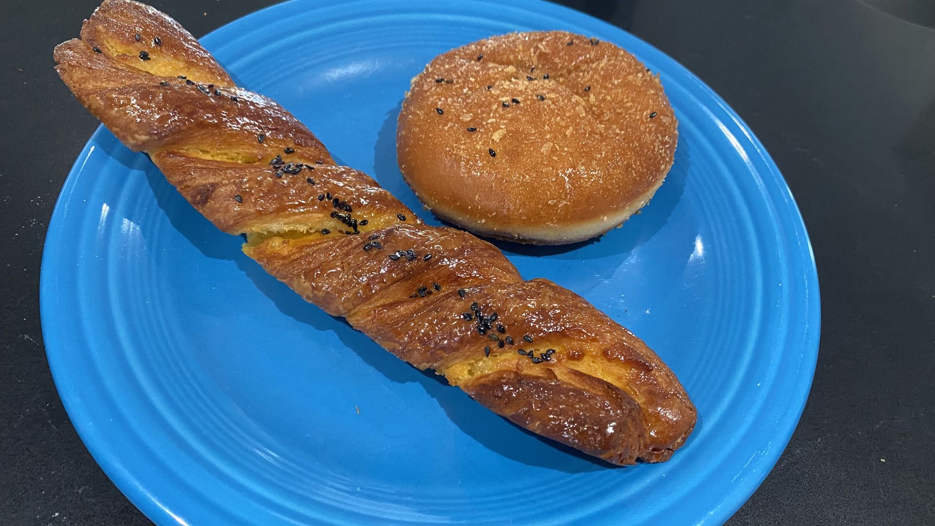 A long, twisted pastry and a round croquette on a blue plate. 