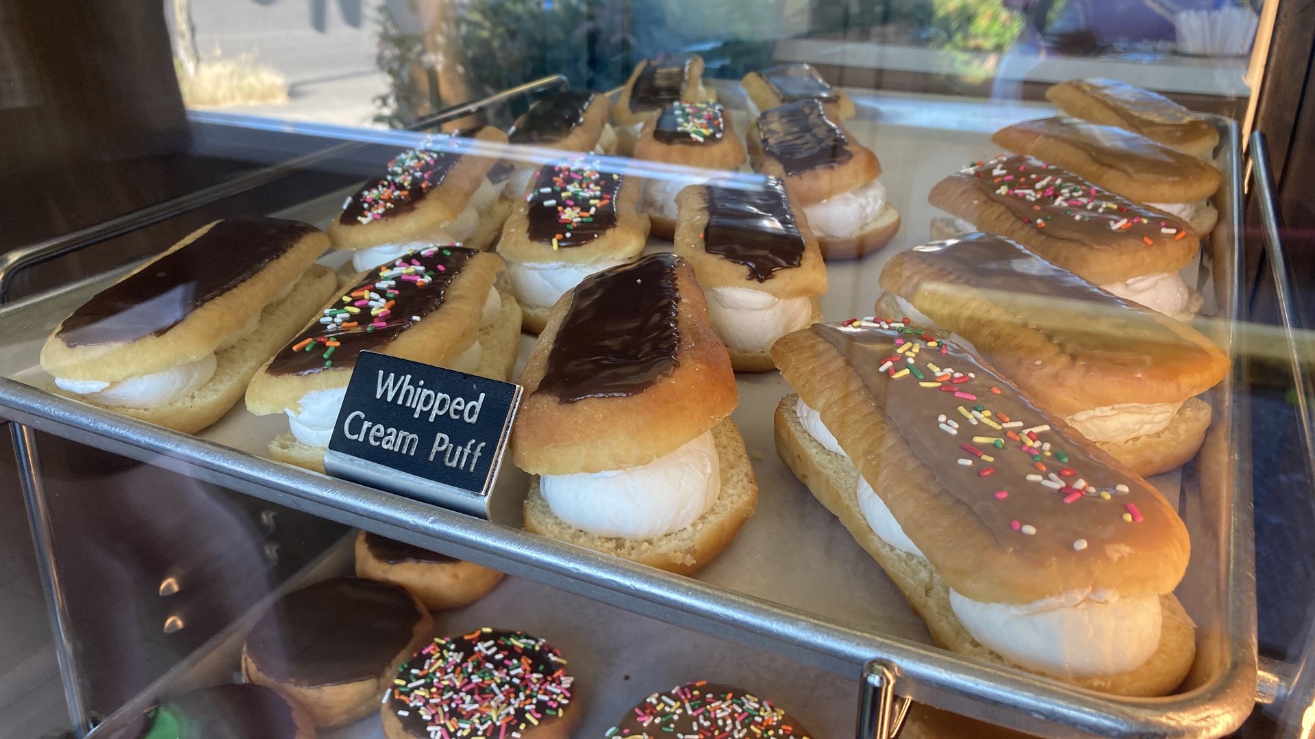 A glass case with a variety of doughnuts displayed.