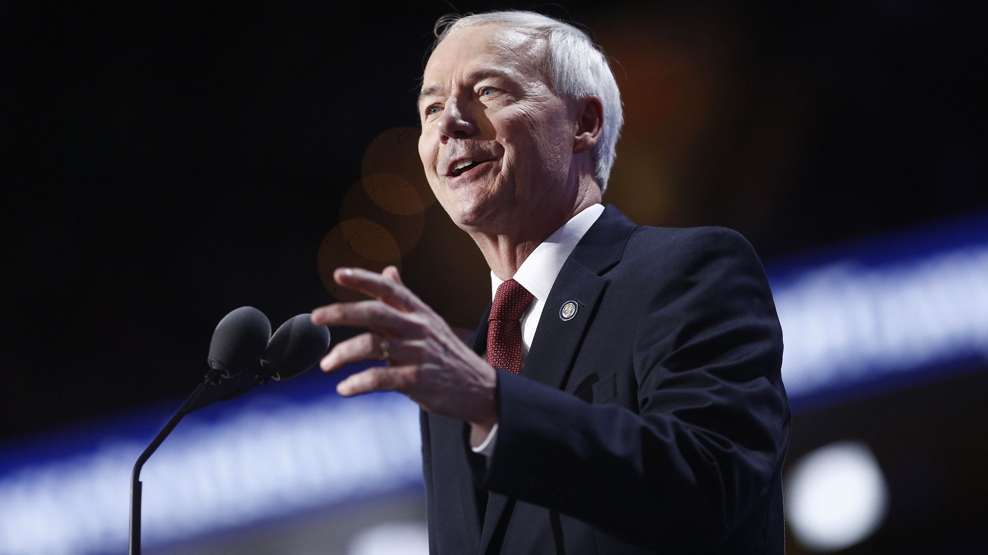 Asa Hutchinson speaks into a microphone while wearing a suit.