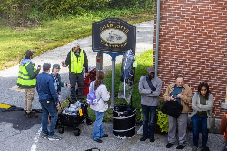 Film crew standing near a blue sign for a Charlotte historic train station for Matt Rife's new movie. 