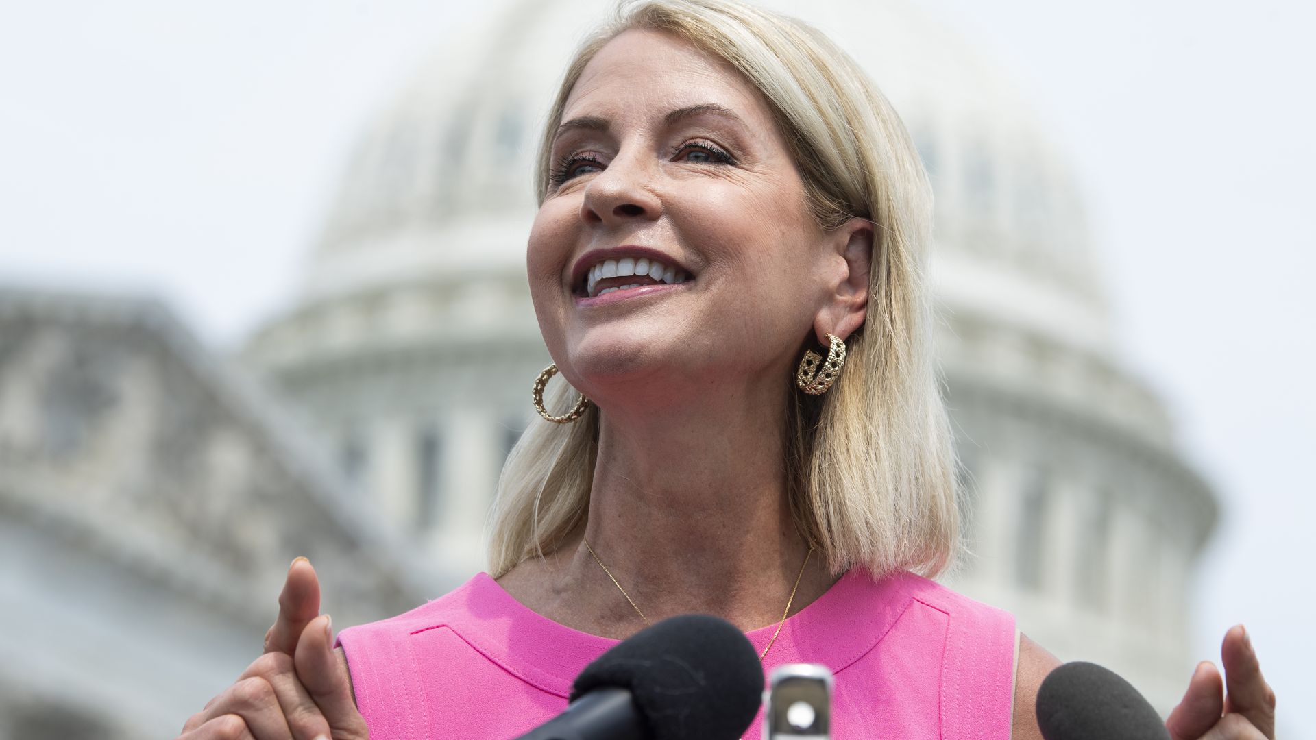 Photo of a woman at a podium in front of the Capitol building.