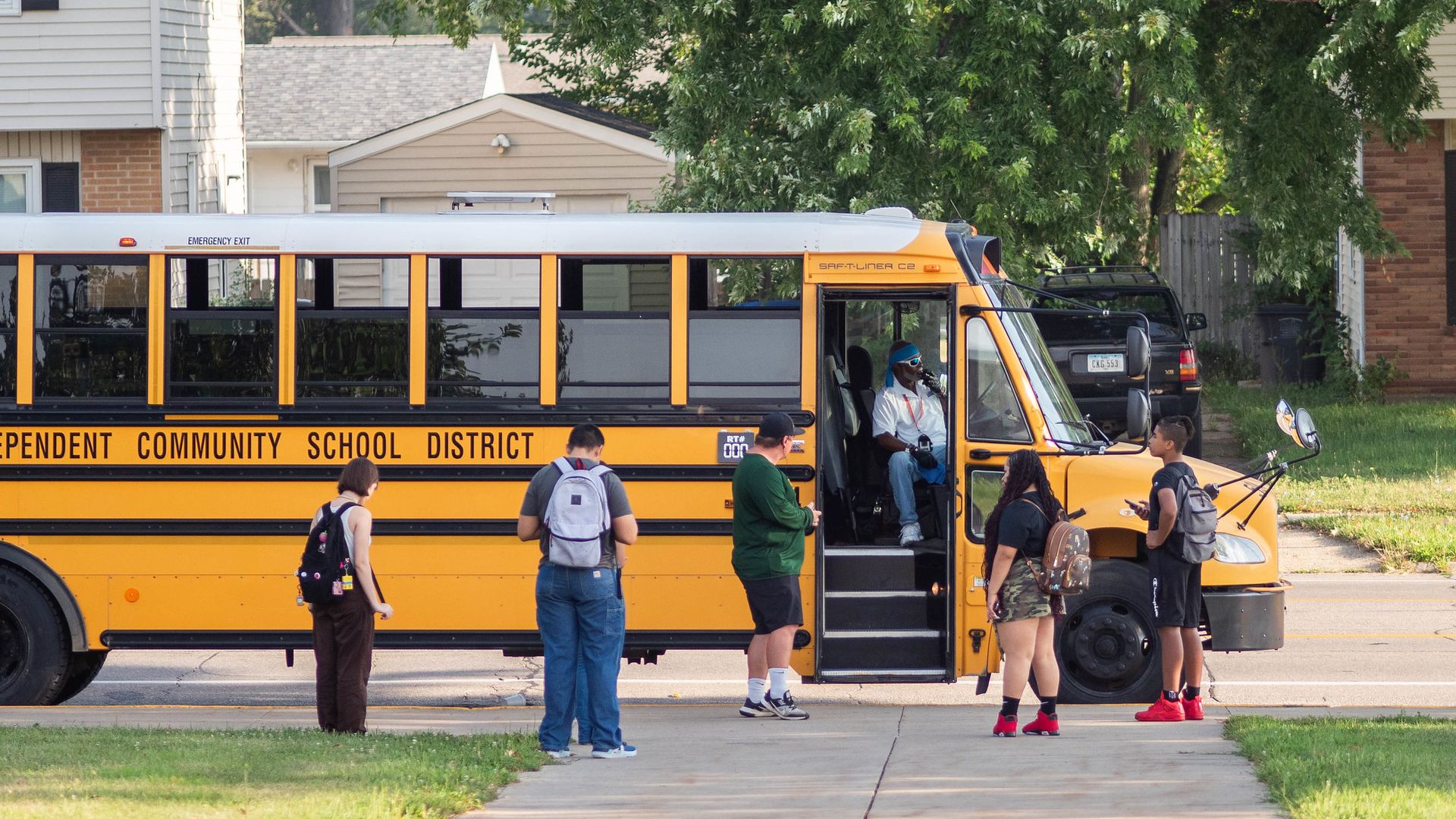 Kids waiting outside of a school bus at Hoover