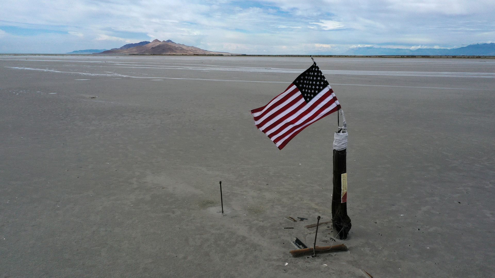 A U.S. flag stands in the sand on the dry shore of the Great Salt Lake. 