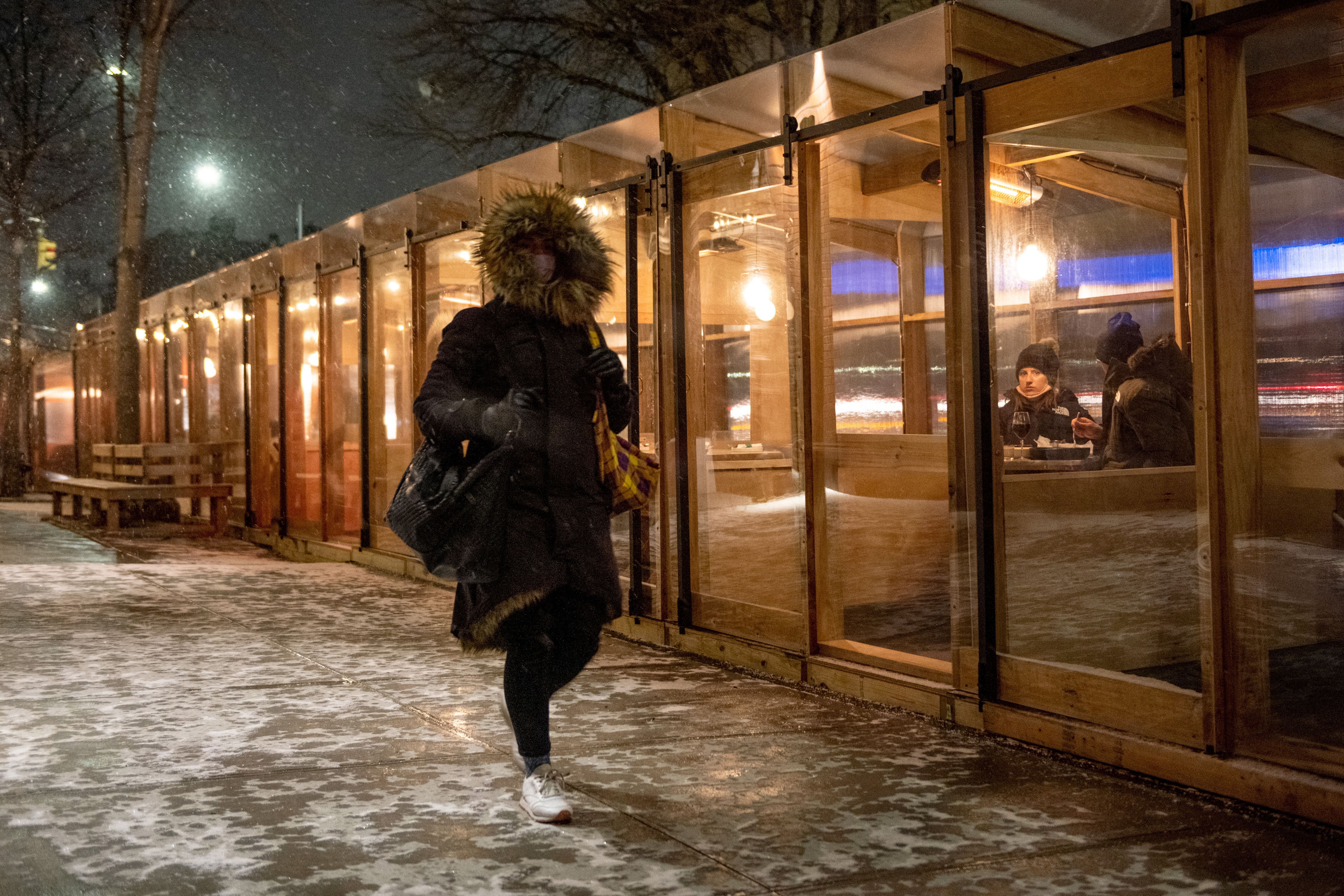 A person passes people iIn Brooklyn's enclosed outdoor dining structure during a Jan. 31 snowstorm in New York City . 