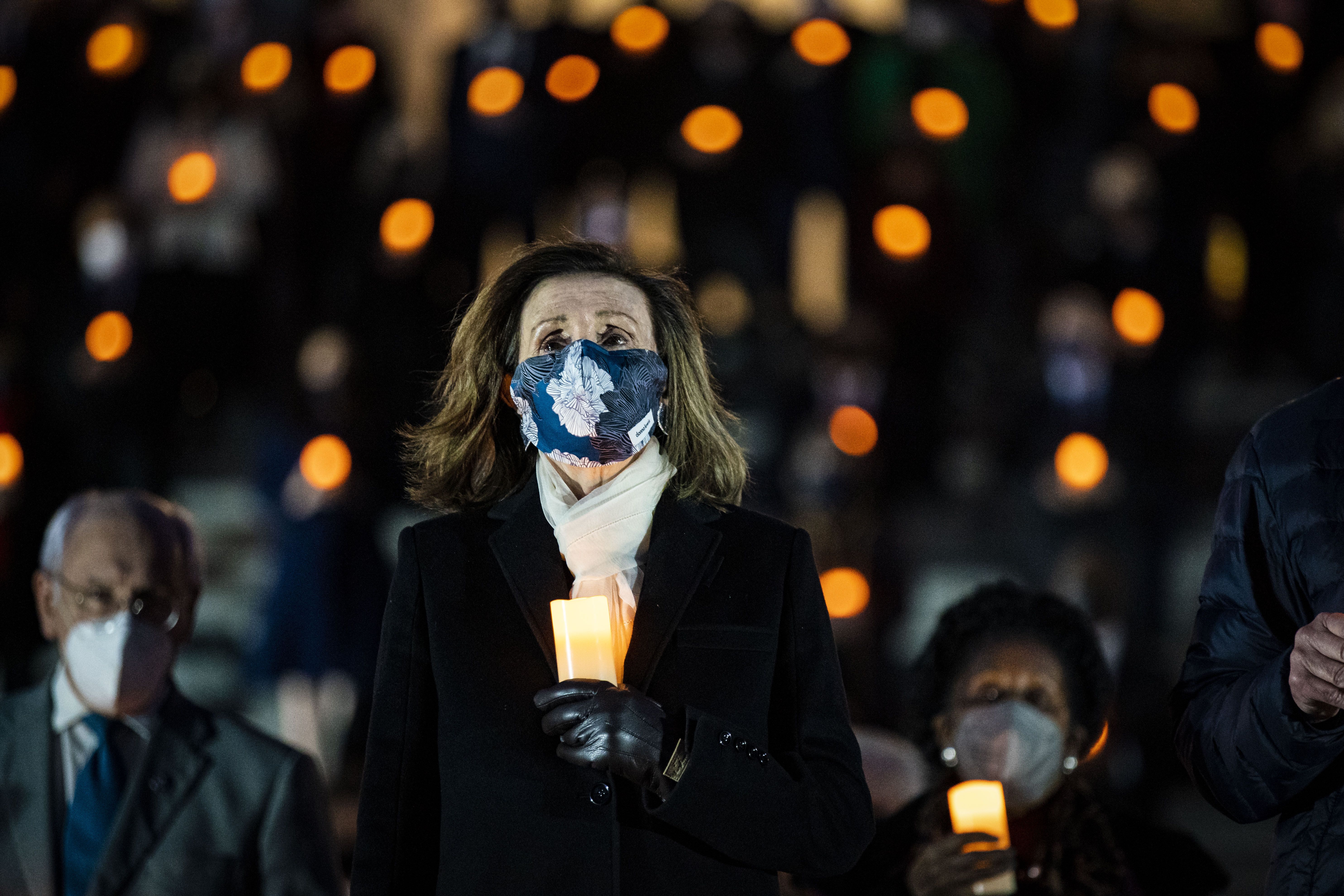 House Speaker Nancy Pelosi outside of the Capitol holding a candle on Feb. 23.
