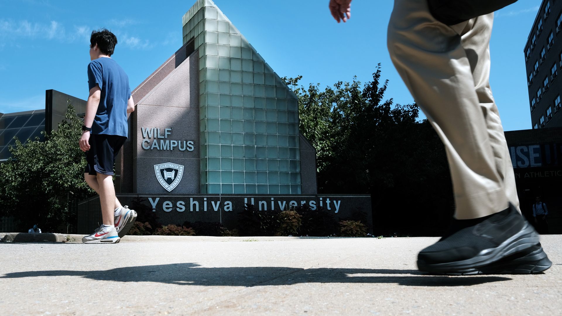 Photo of people walking by a building that says "Yeshiva University, WILF campus"
