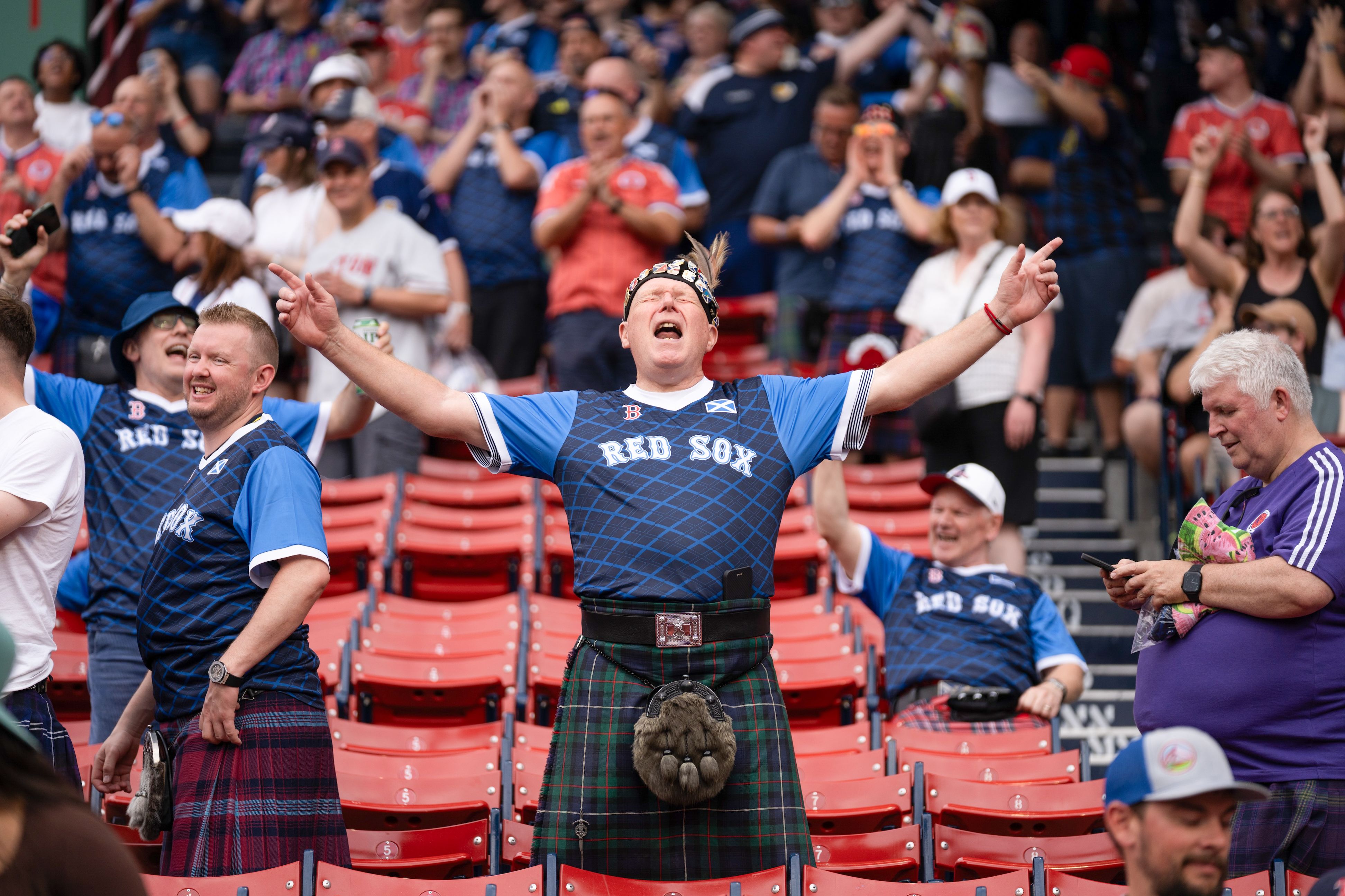 A fan in a Scottish kilt and a Red Sox jersey cheers in the stands