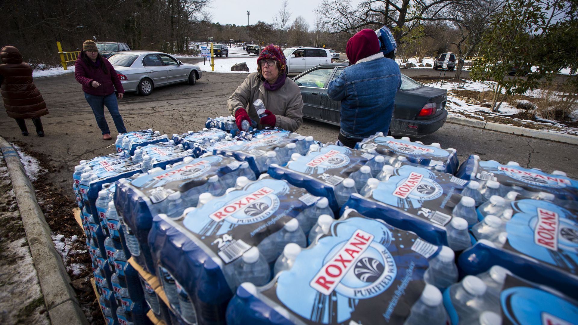 giant cases of water with volunteers around it bundled up.