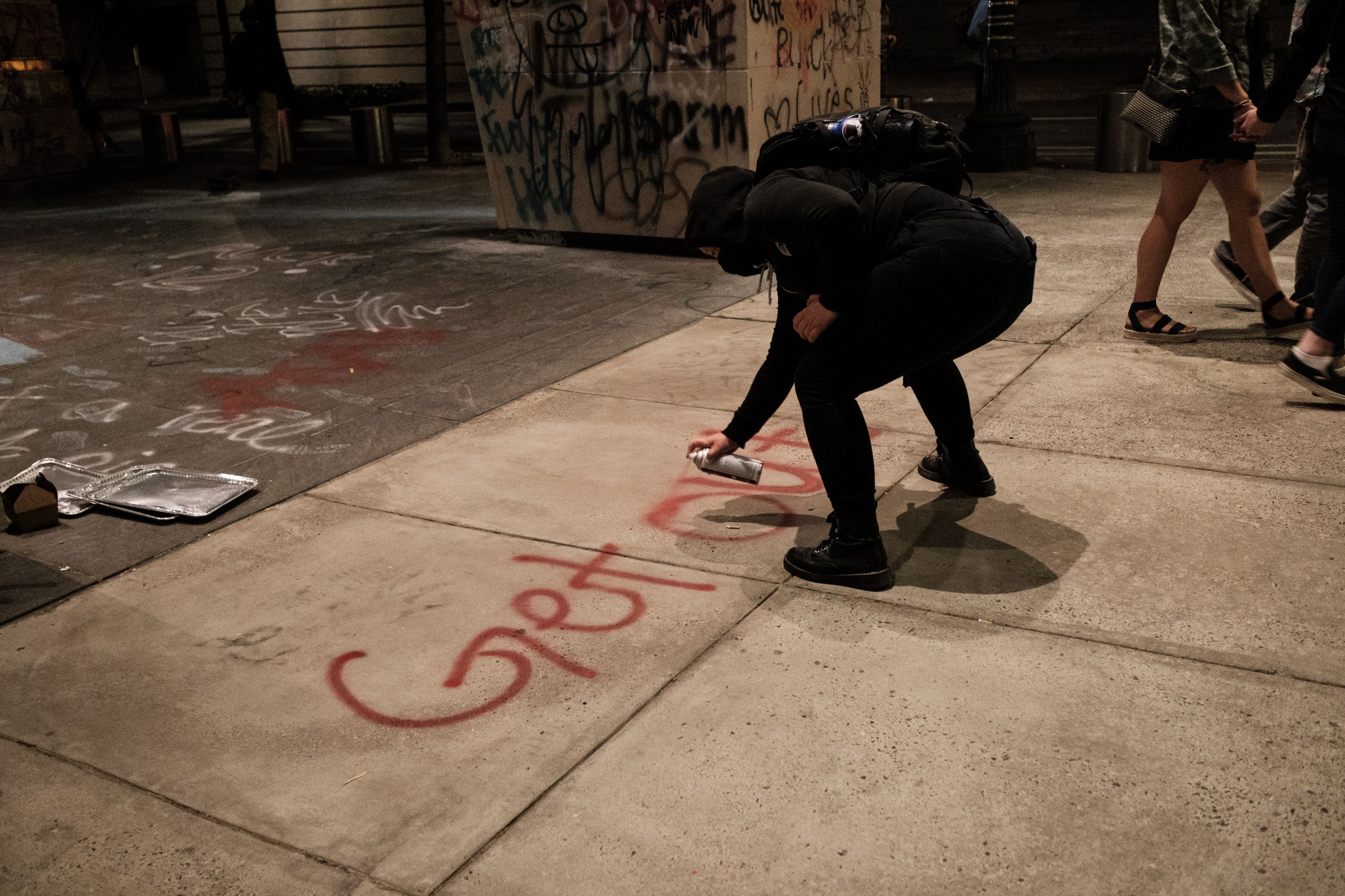 A protestor painting "get out" on the sidewalk. Photo: Mason Trinca/Getty Images