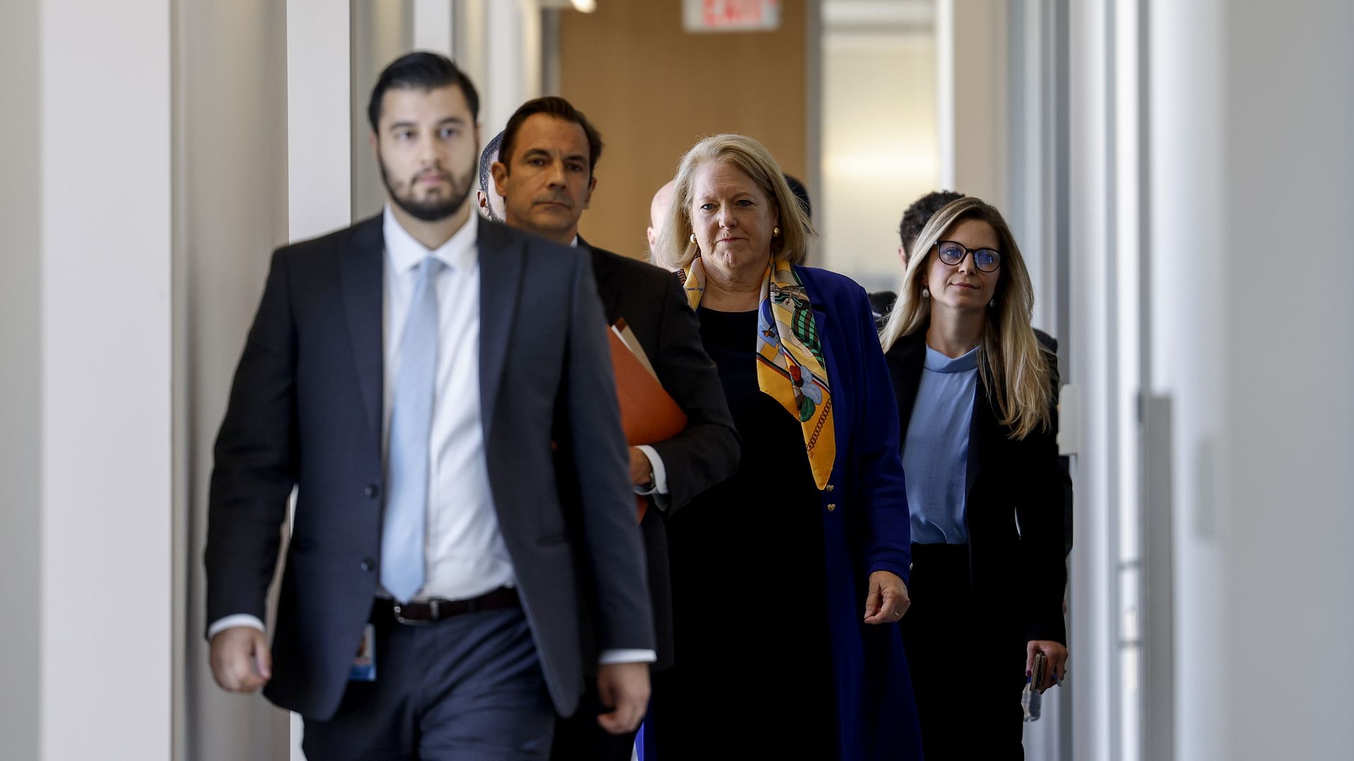 Ginni Thomas, wearing a blue jacket and yellow scarf, walks to a Jan. 6 committee hearing at the O'Neill House Office Building.