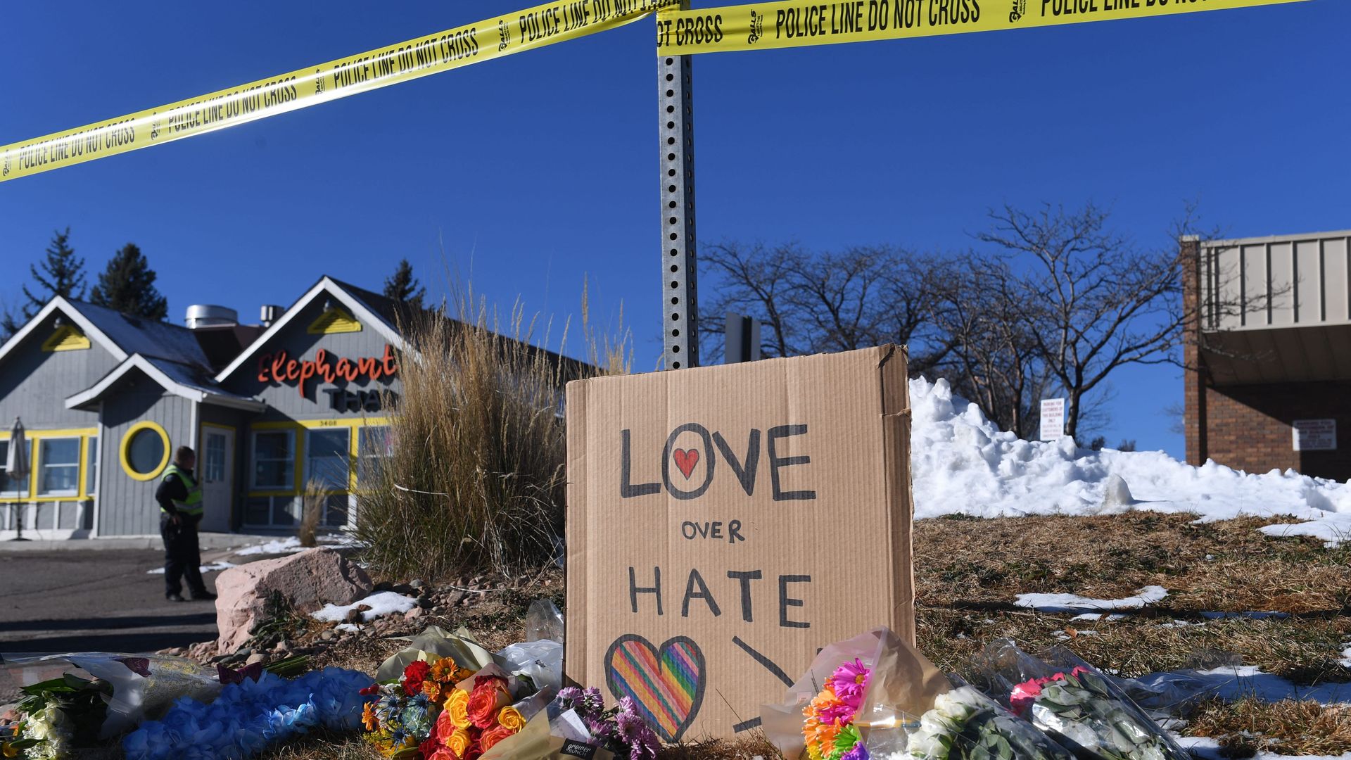 Bouquets of flowers and a sign reading "Love Over Hate" are left near Club Q