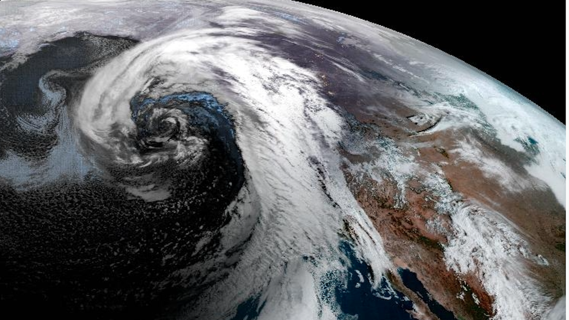 Satellite view of a large, comma-shaped cloud swirling over the northeast Pacific Ocean, dragging an atmospheric river into California.
