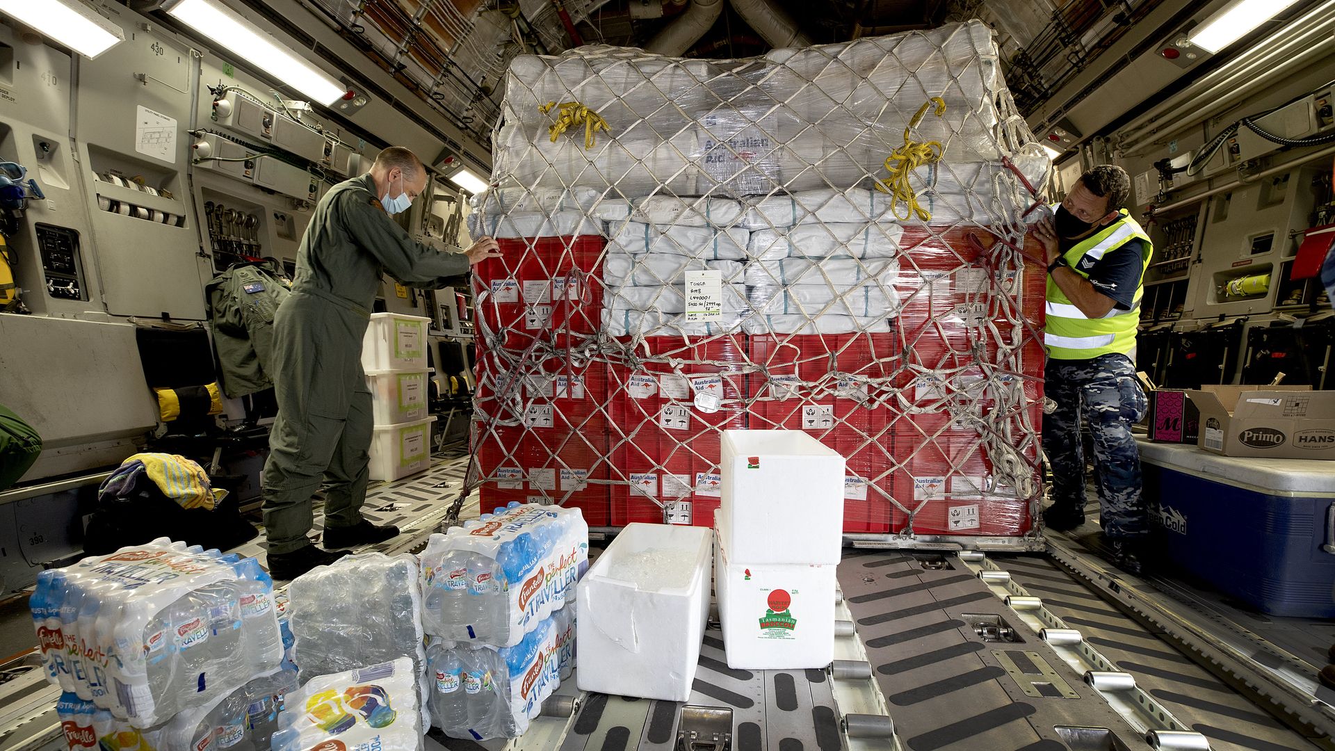 Air Force Load Master Corporal Dale Hall (L) helps secure humanitarian aid supplies aboard a Royal Australian Air Force C-17A Globemaster III aircraft.