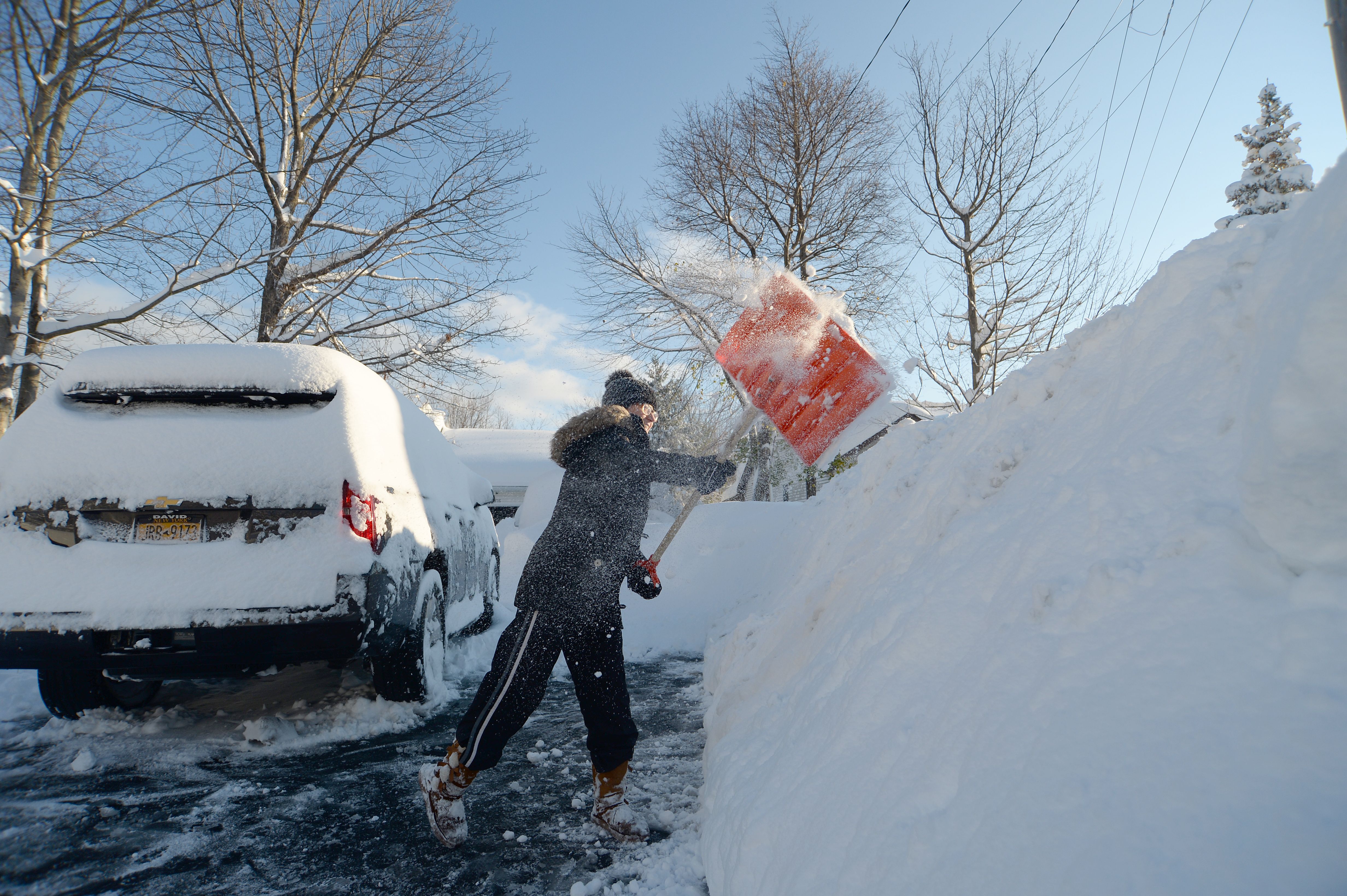 A person clearing snow from around a vehicle in Hamburg, New York, on Nov. 19.