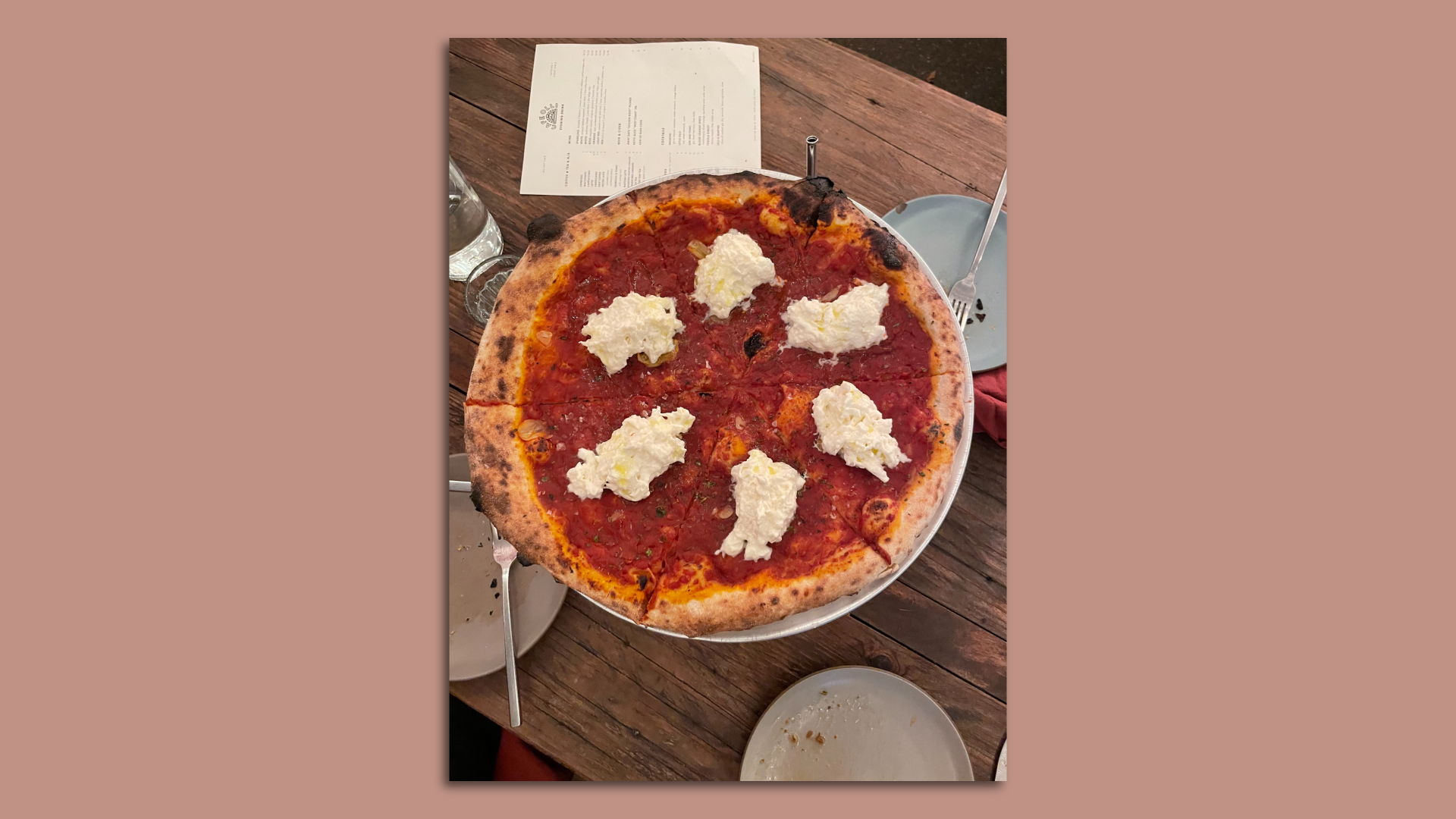 A pizza with tomato sauce and a clump of white stracciatella on each slice.