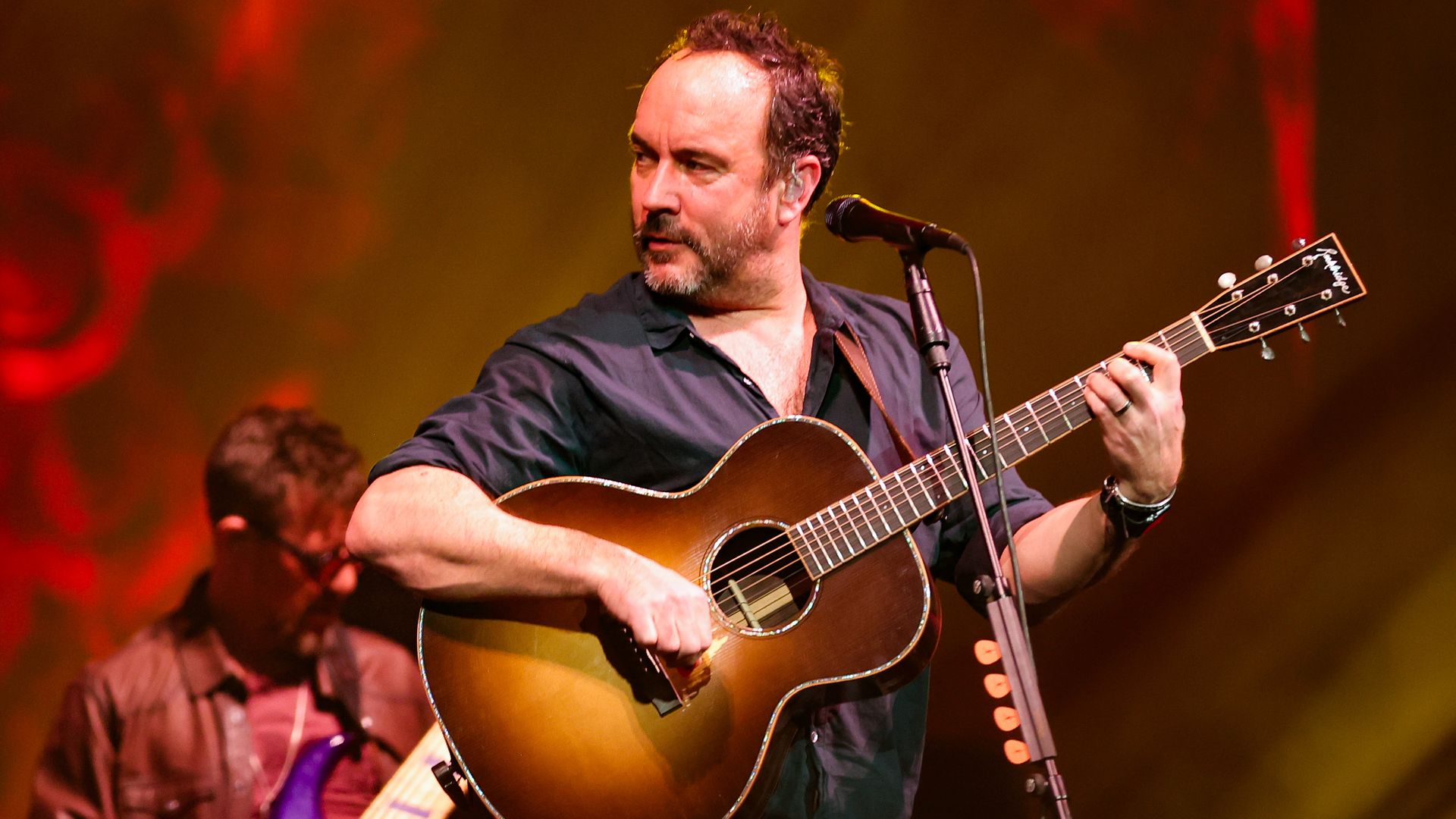 Photo of Dave Matthews playing a guitar on stage. 