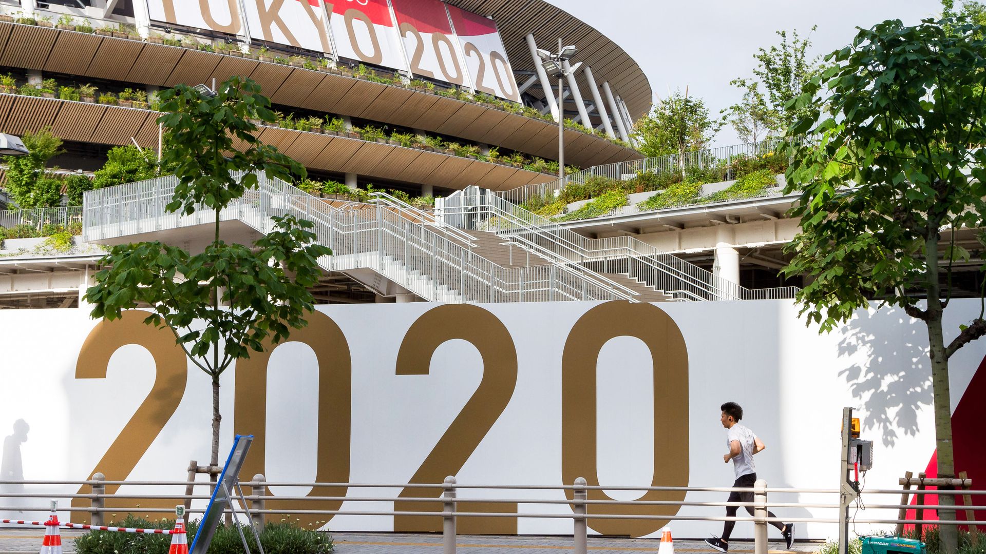 A jogger runs past a large Tokyo 2020 sign around the National Olympic stadium, Gaiemmae on July 3