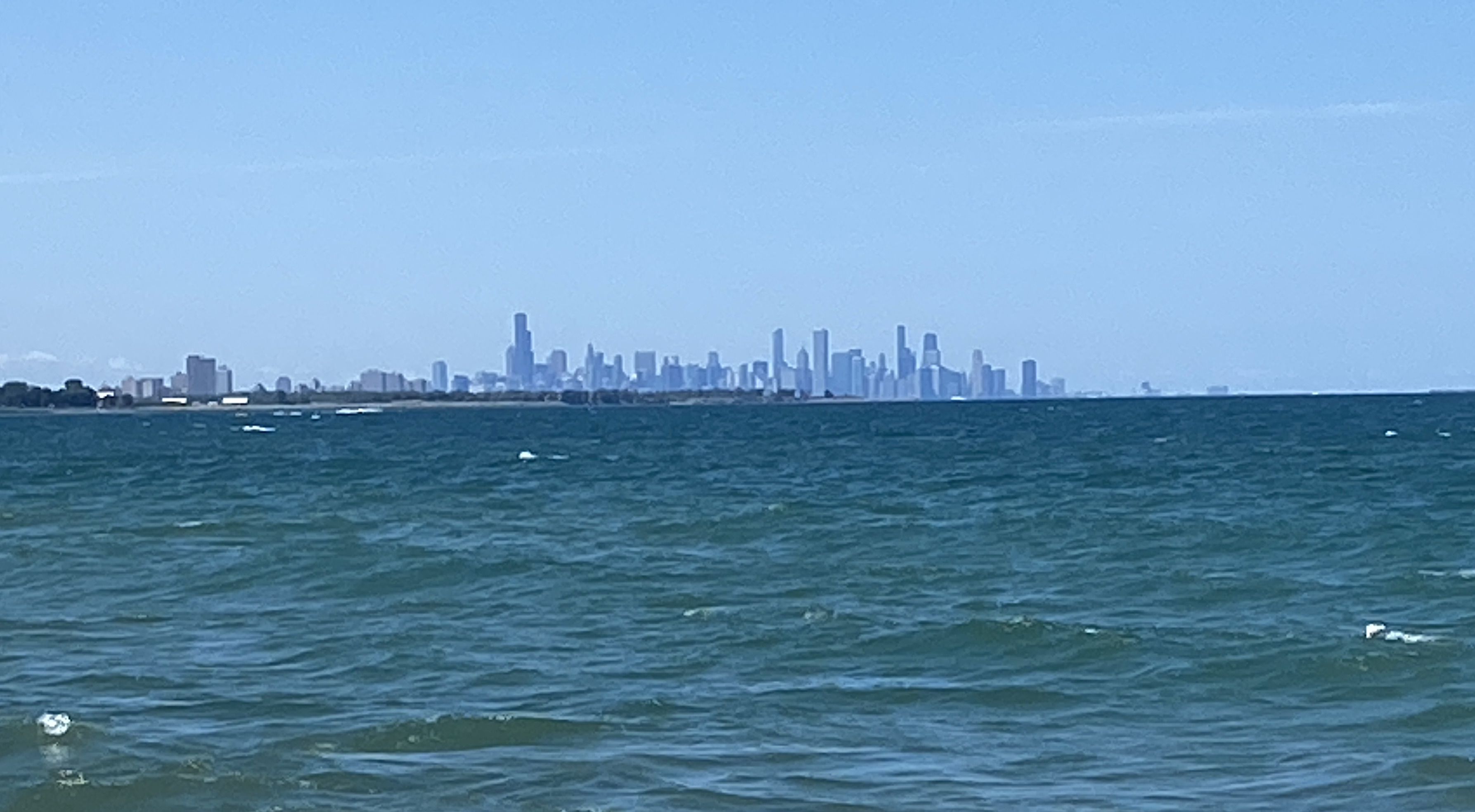 Distant view of Chicago skyline behind Lake Michigan.