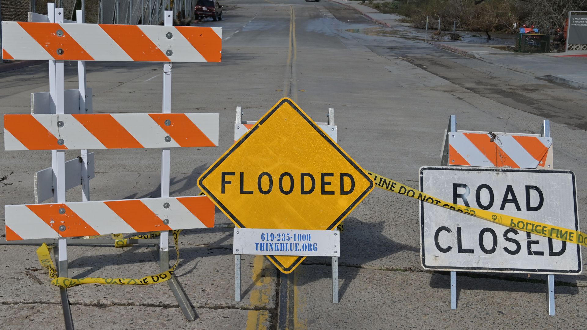 Signs and barriers mark a closed road due to flooding.
