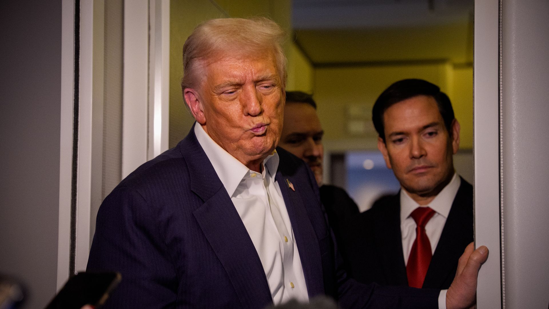 Trump wearing a blue suit jacket and white shirt and Rubio wearing a dark suit jacket, white shirt and red tie. 