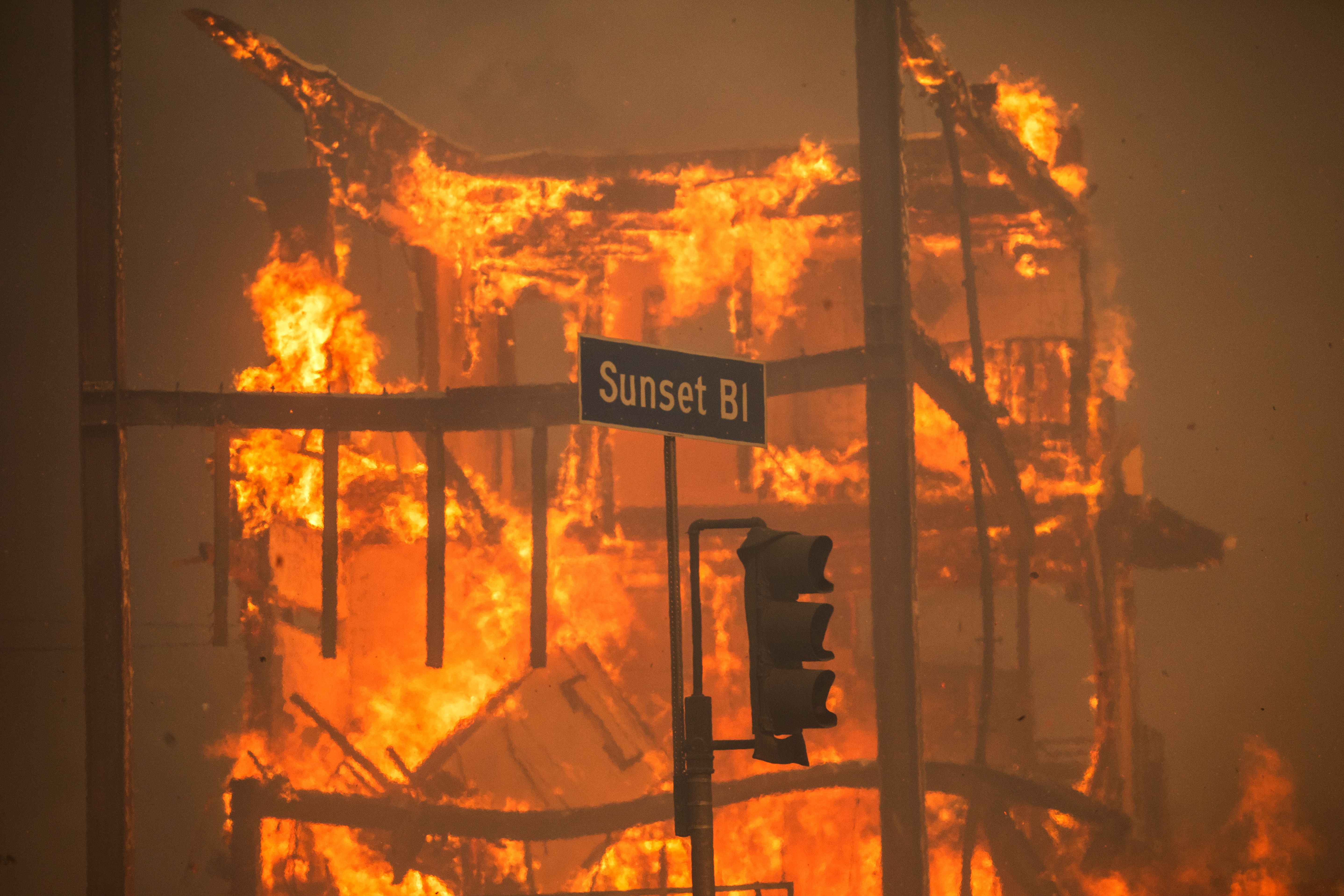 LOS ANGELES, CALIFORNIA - JANUARY 8: Flames from the Palisades Fire burn a building on Sunset Boulevard amid a powerful windstorm on January 8, 2025 in the Pacific Palisades neighborhood of Los Angeles, California. Fueled by intense Santa Ana Winds, the Palisades Fire has grown to over 15,000 acres