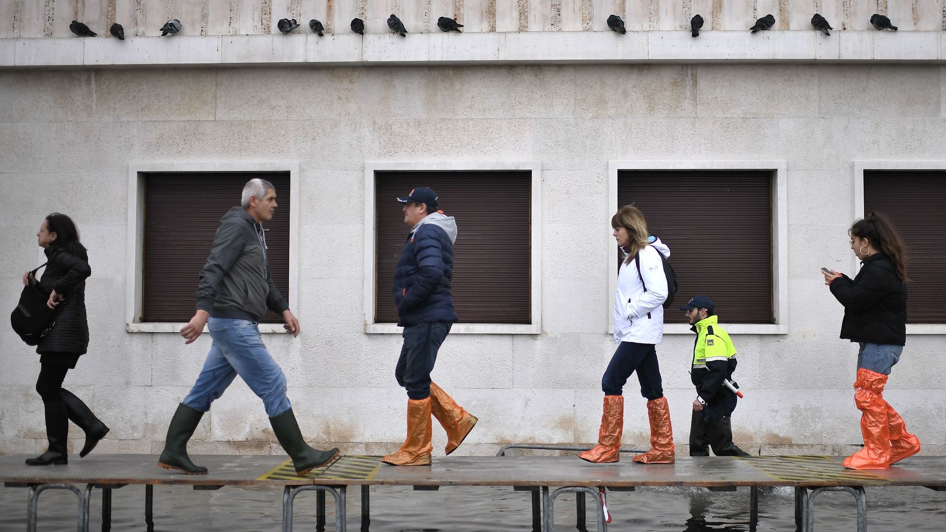 People walk on a footbridge across a flooded street in Venice.