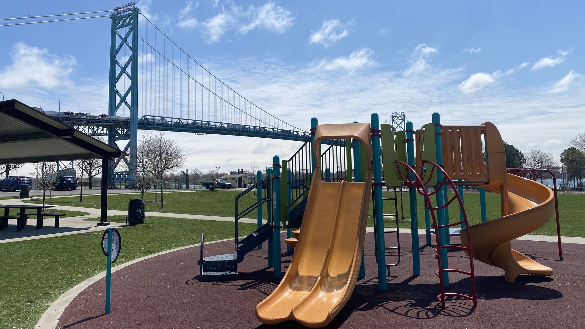 A playset is shown at Riverside Park, with the Ambassador Bridge in the background.