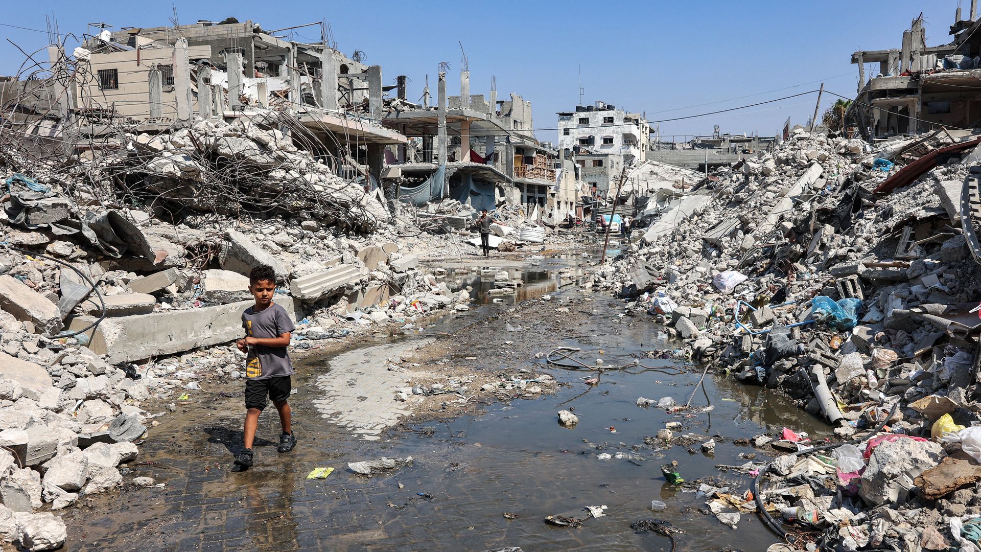 A boy walks past mounds of trash and rubble along a street in the Jabalia camp for Palestinian refugees in the northern Gaza Strip on August 14, 2024 