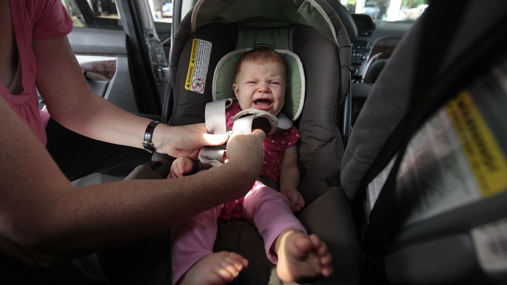 A baby gets buckled into a rear facing car seat 