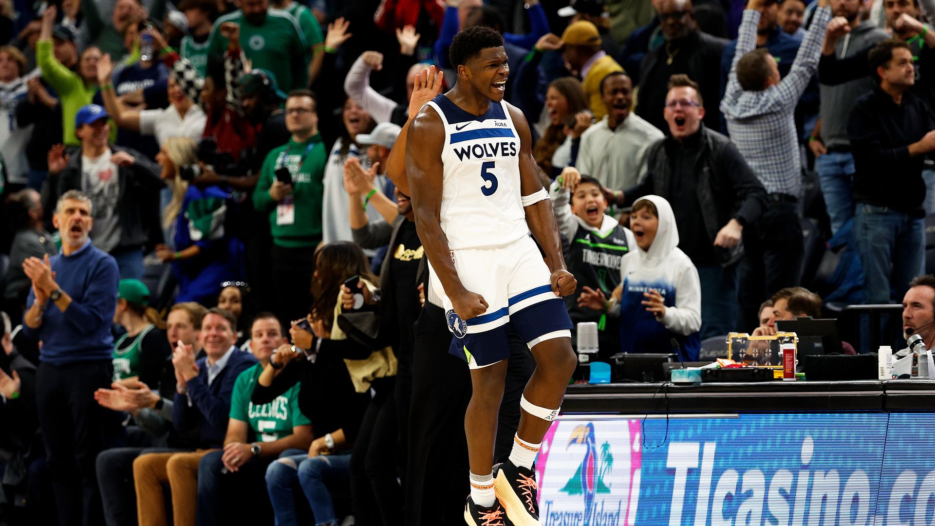 Anthony Edwards celebrates as fans behind him jump up and down