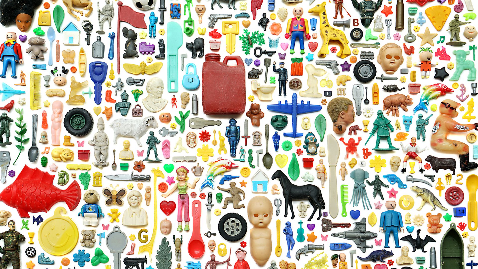 Image of many assorted, small plastic objects like doll heads, planes, eating utensils, arranged into a montage.