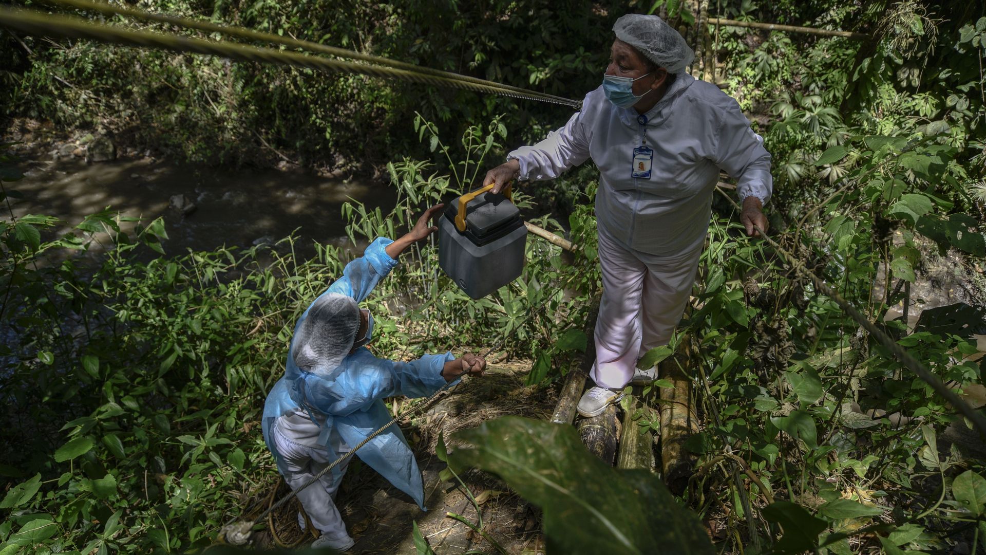 In Colombia, a vaccination brigade wades through jungle areas to reach rural inhabitants July 3. Photo: Guillermo Legaria/Getty Images