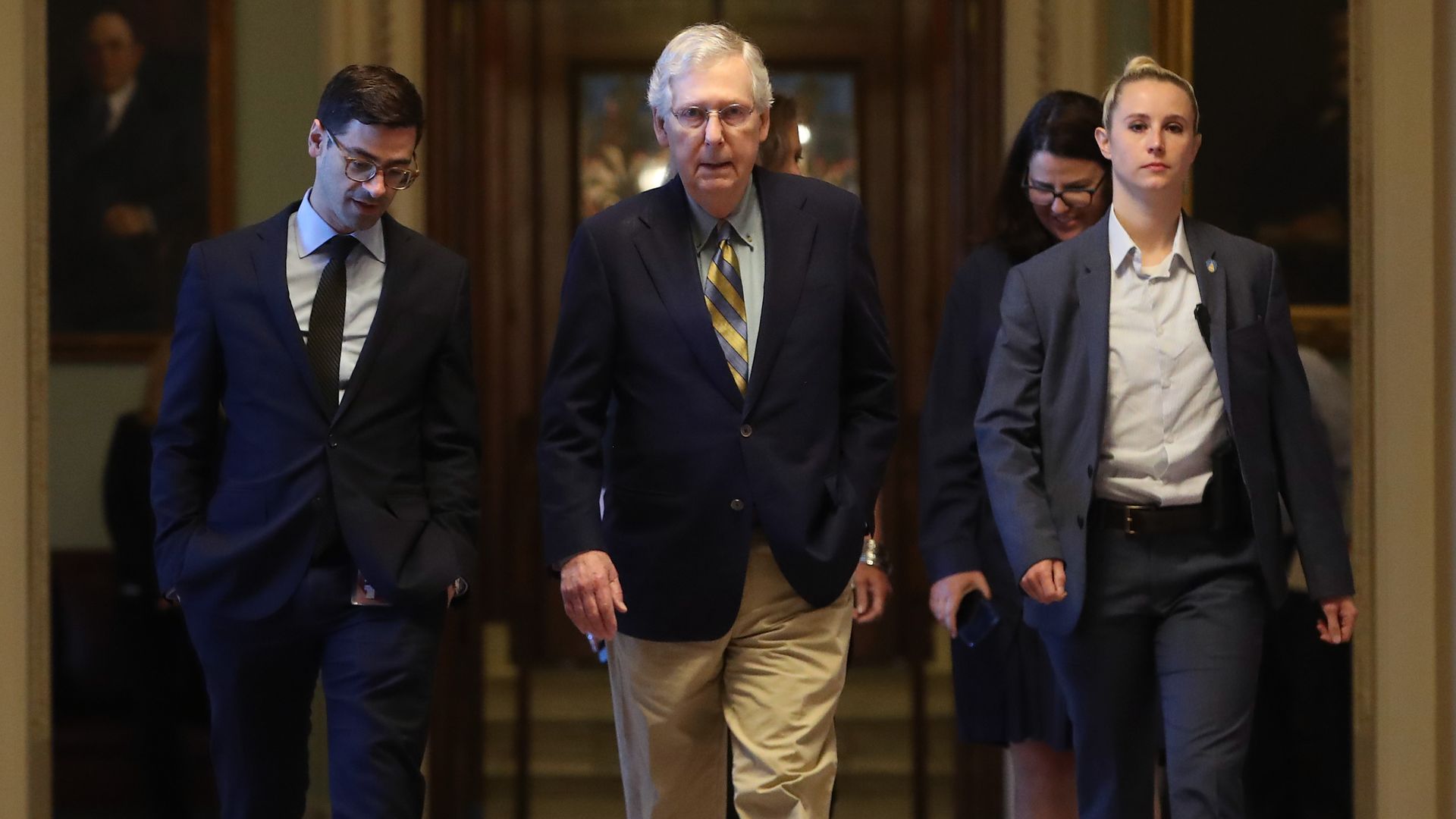 Senate Majority Leader Mitch McConnell of Kentucky walks through the Senate with two aides.