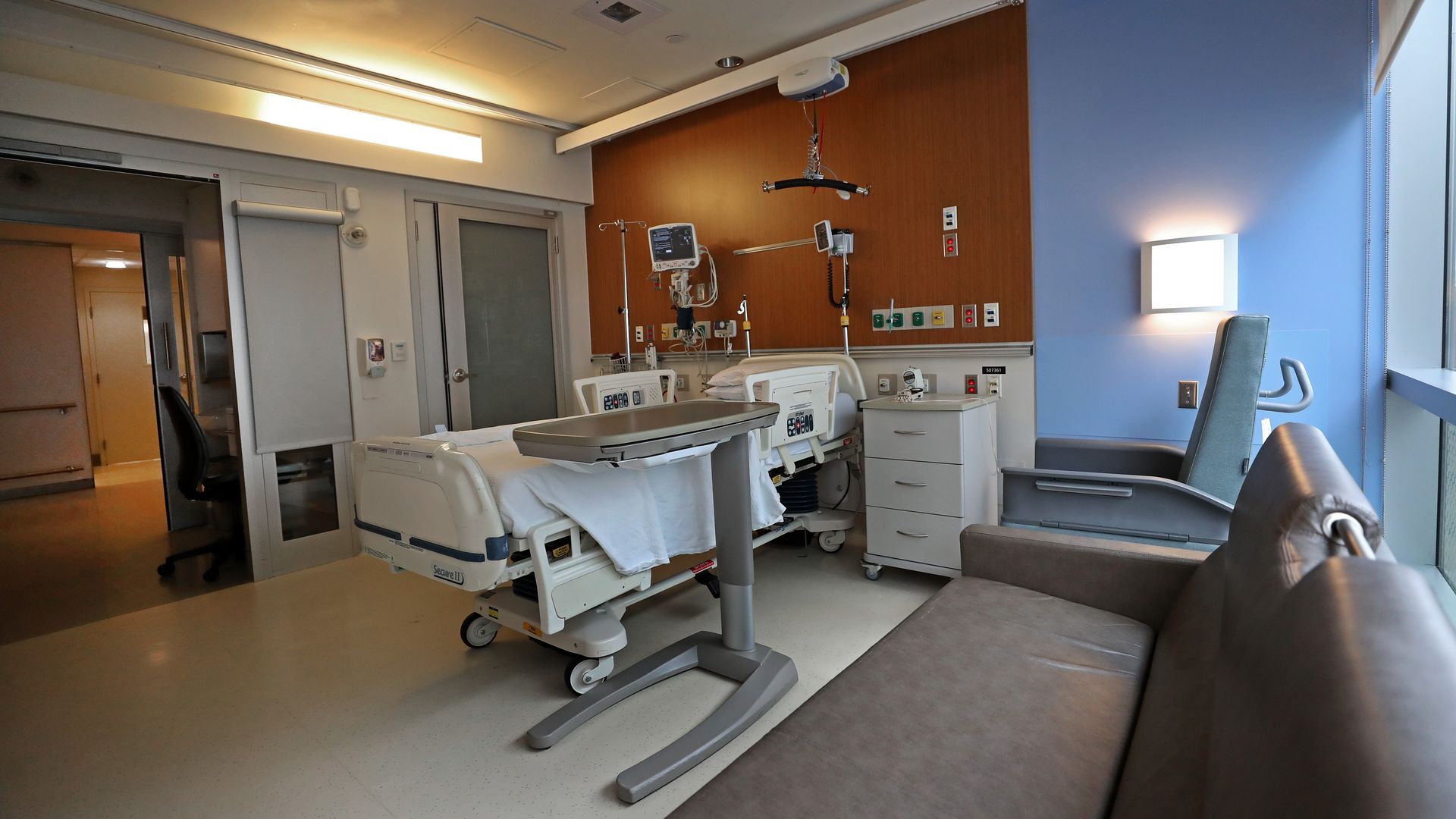 A hospital bed and equipment in an empty patient room.