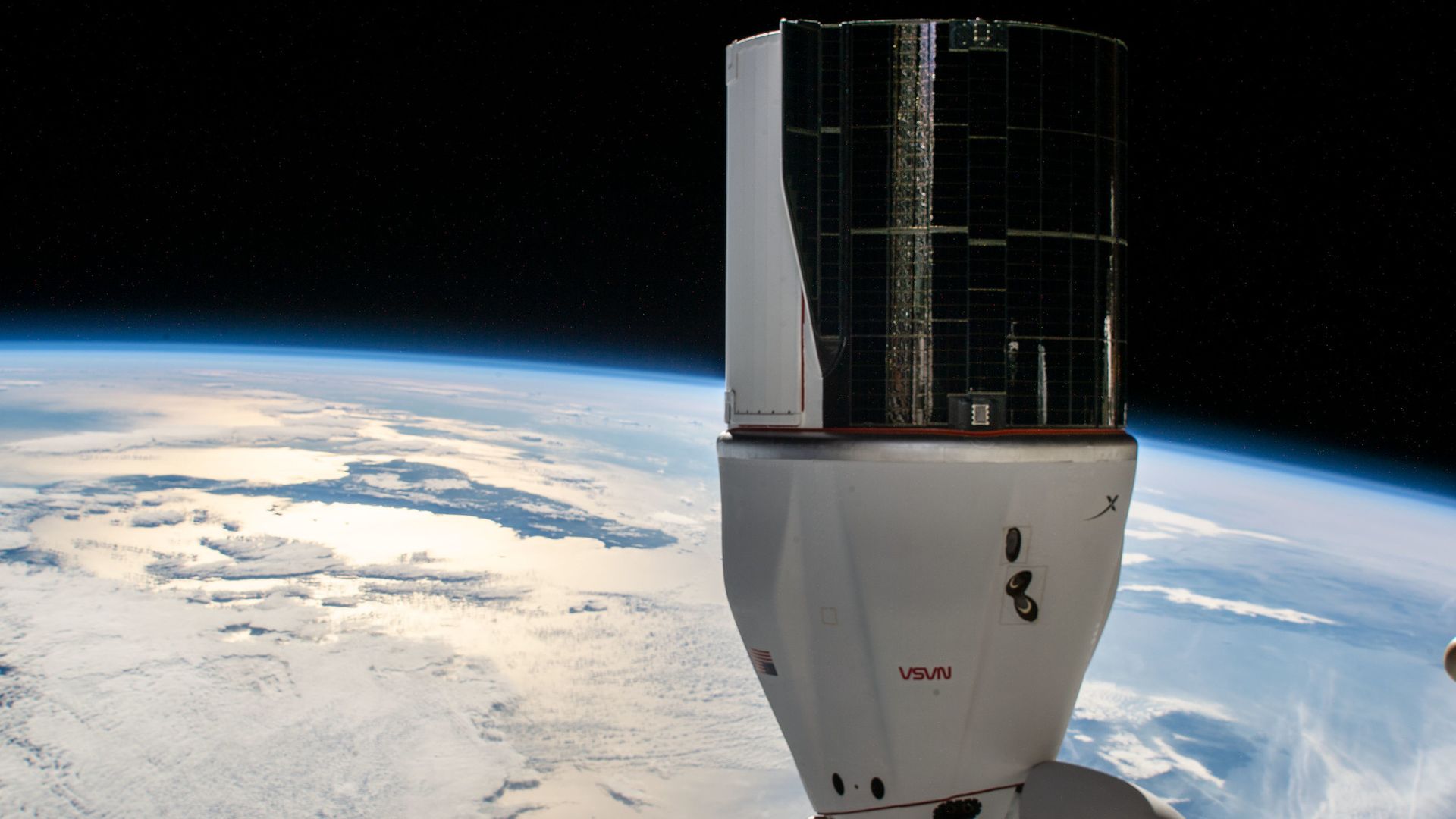 SpaceX Dragon attached to the International Space Station with the limb of the Earth stretching behind