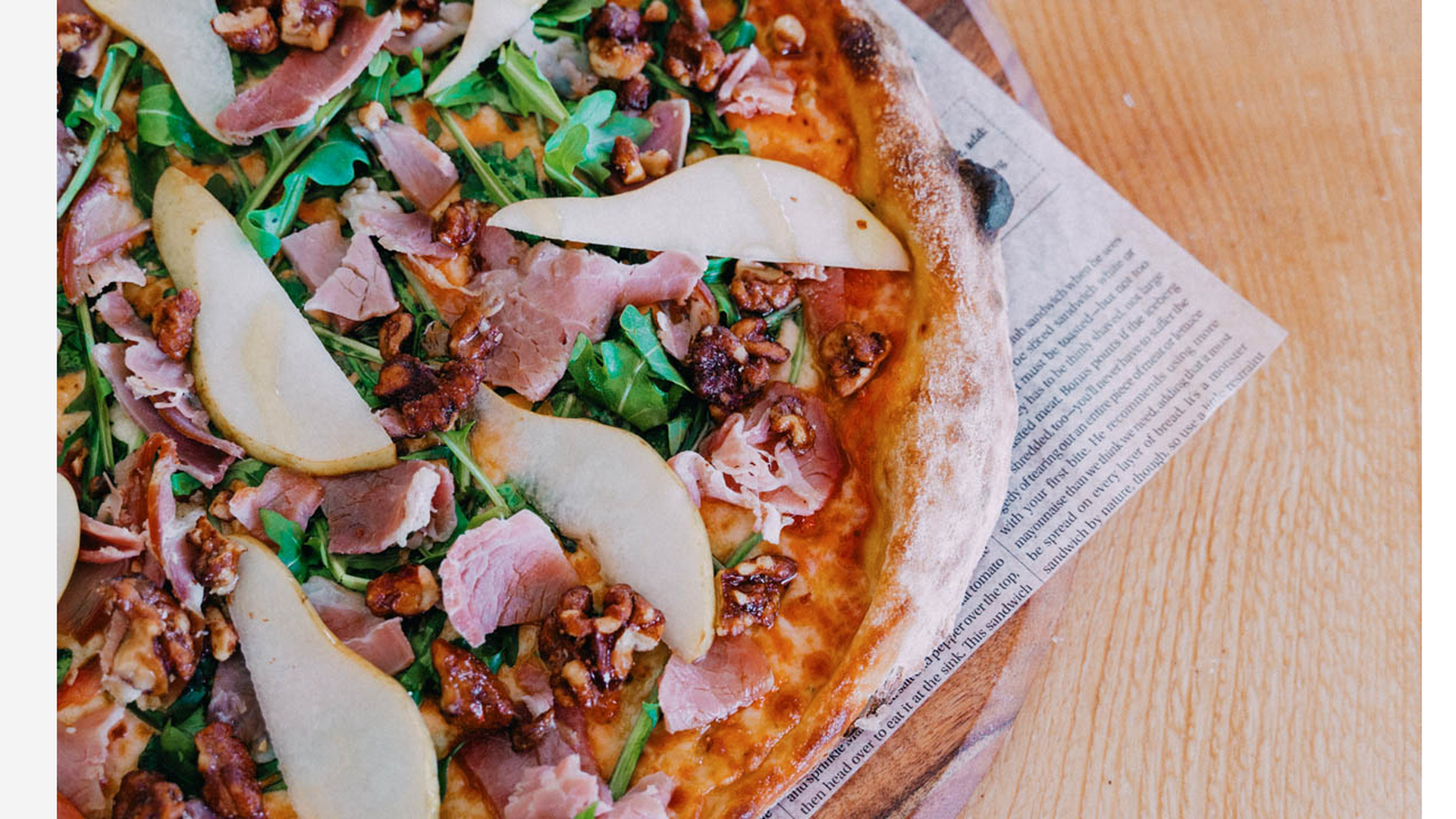 a photo of a pizza with sliced pear, prosciutto and blue cheese.