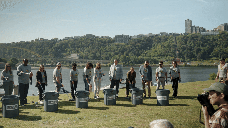 A group of people toss litter into trash cans.