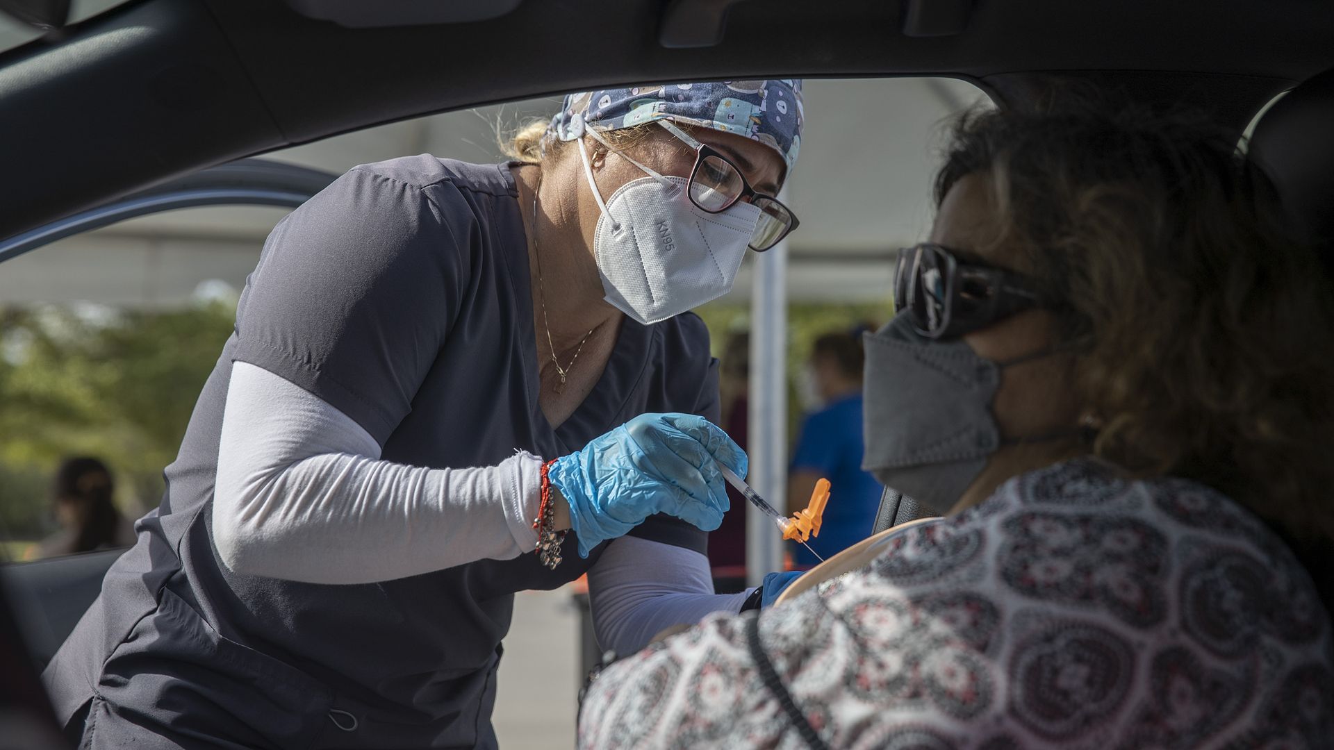 A healthcare worker administers a Pfizer-BioNTech COVID-19 vaccine to a person at a drive-thru site in Tropical Park on December 16, 2021 in Miami, Florida.
