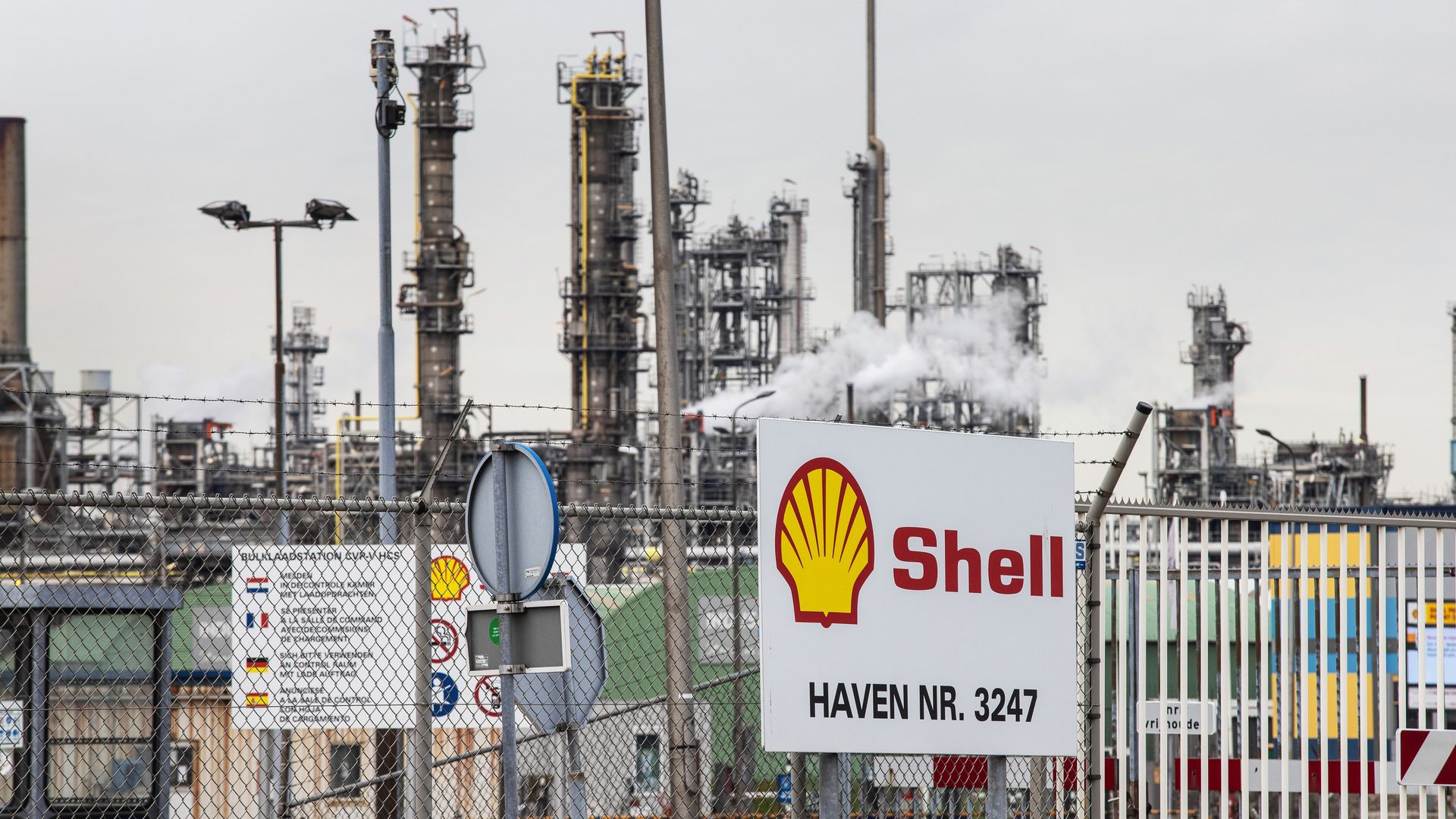 Sign saying "Shell" in front of an oil refinery.