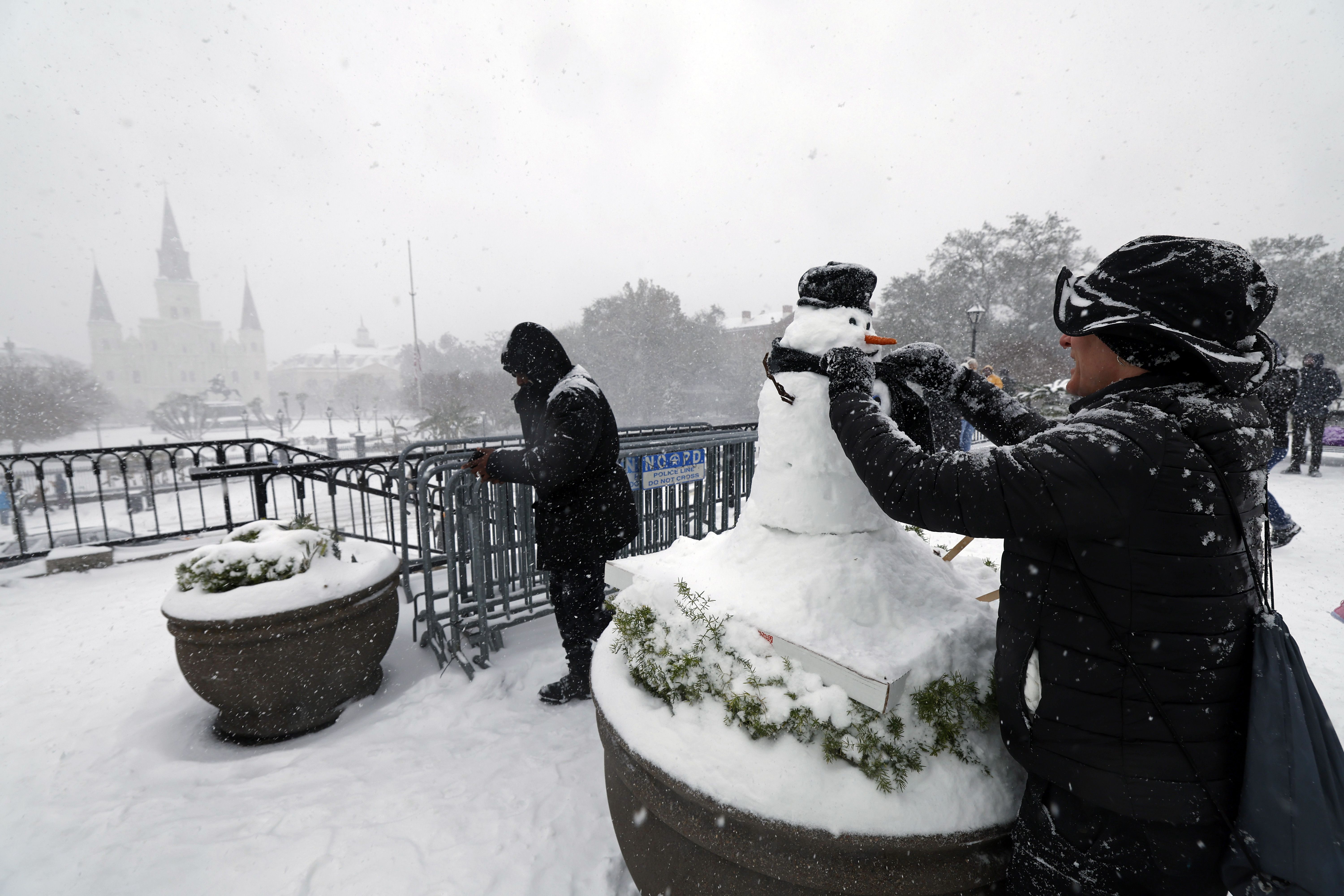Photo shows a person building a snowman near Jackson Square.