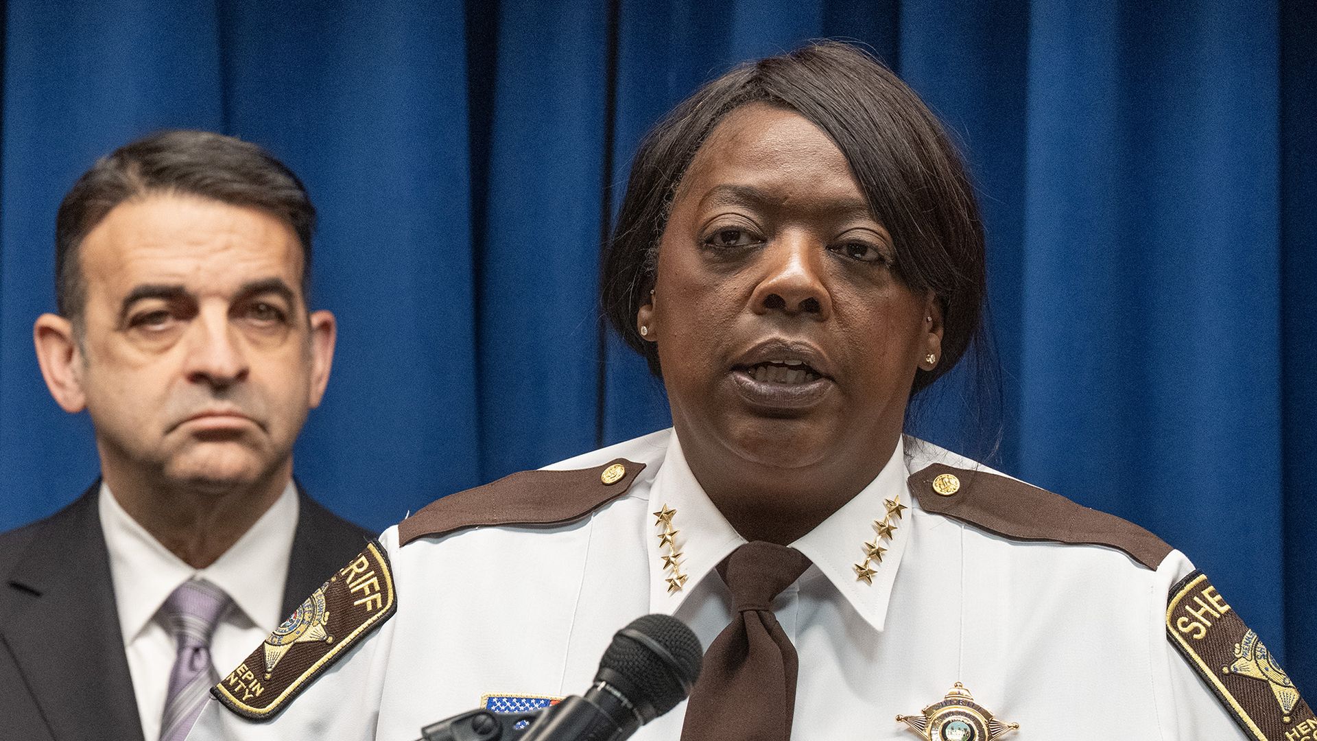 A woman in a white sheriff's department uniform with four brass stars and brown epaulets