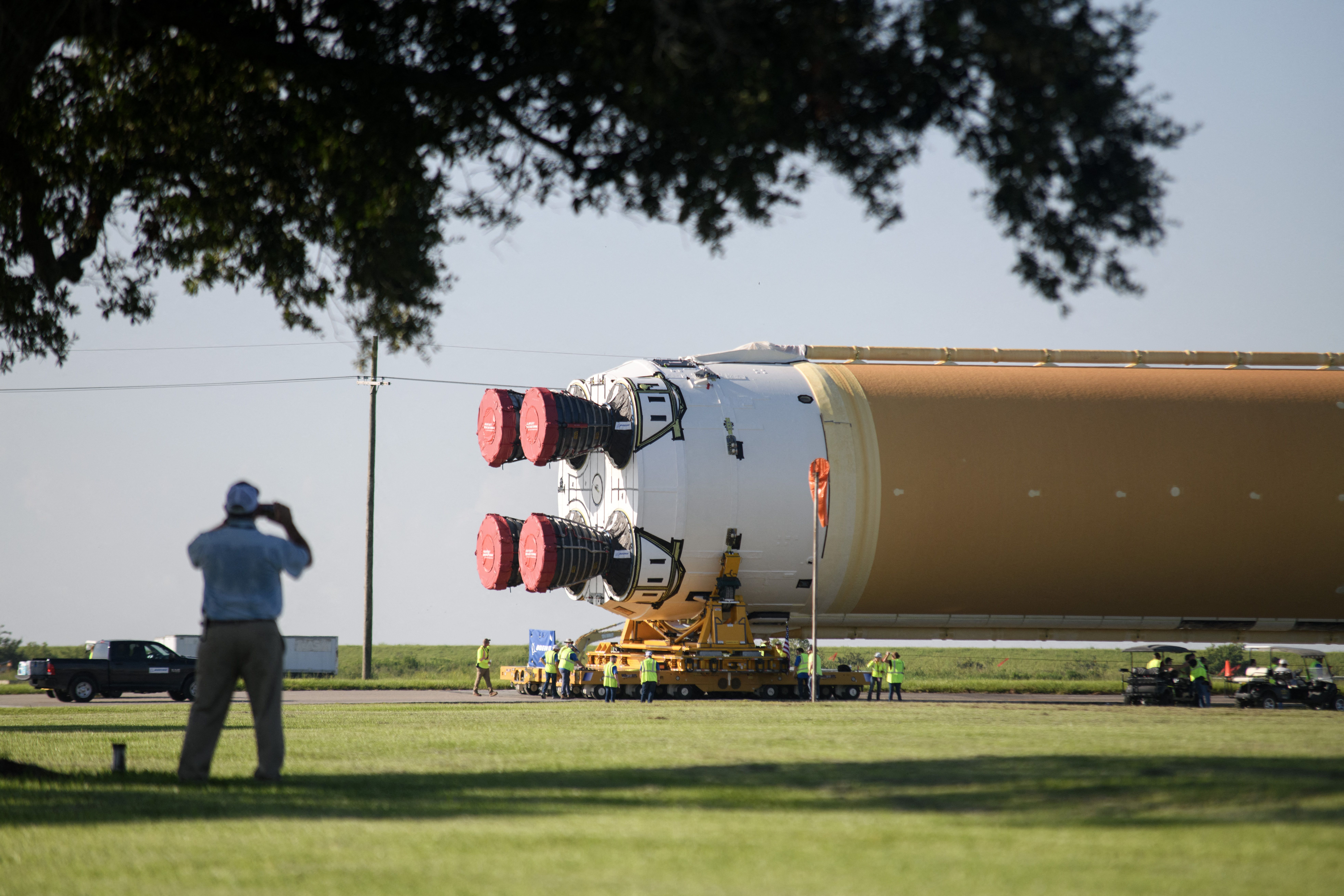 TOPSHOT - A man takes a photo as the Artemis II rocket core stage is wheeled out at the NASA Michoud Assembly Facility in New Orleans, Louisiana, on July 16, 2024. The stage will launch the first crewed Artemis mission. (Photo by Mark Felix / AFP) (Photo by MARK FELIX/AFP /AFP via Getty Images)