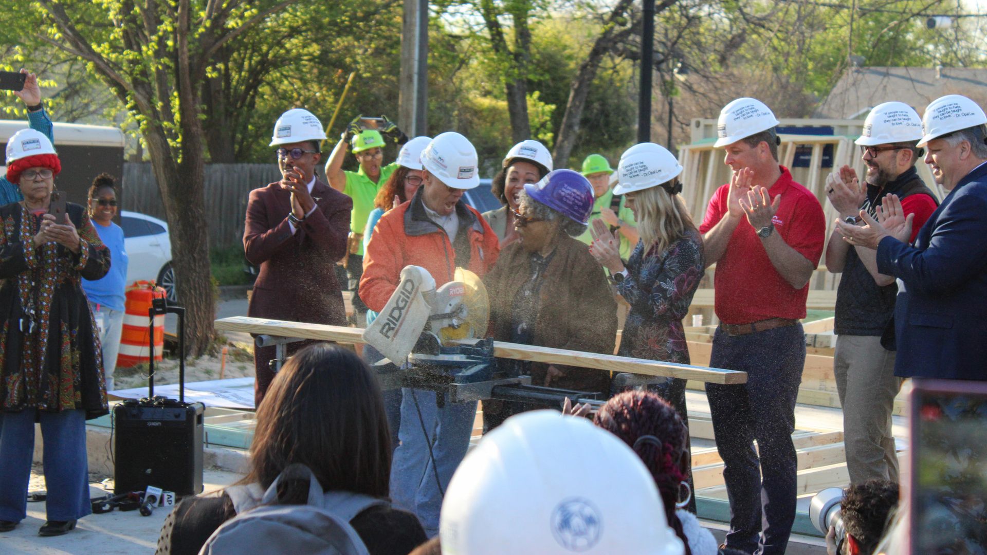 Several people standing in a line with a woman and an electric saw