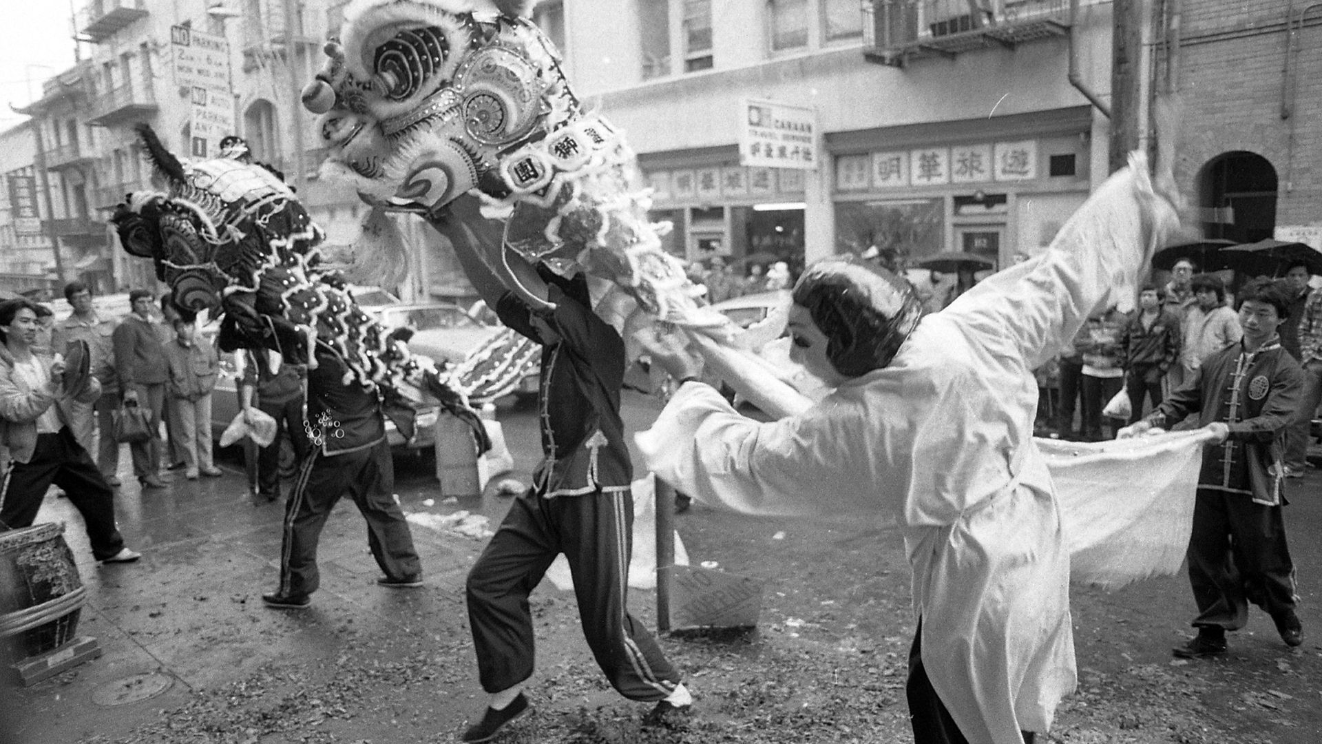 A Chinese New Year parade featuring lion dance performers in a black and white photo