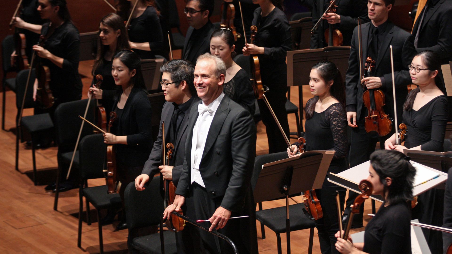 A conductor stands in front of an orchestra.