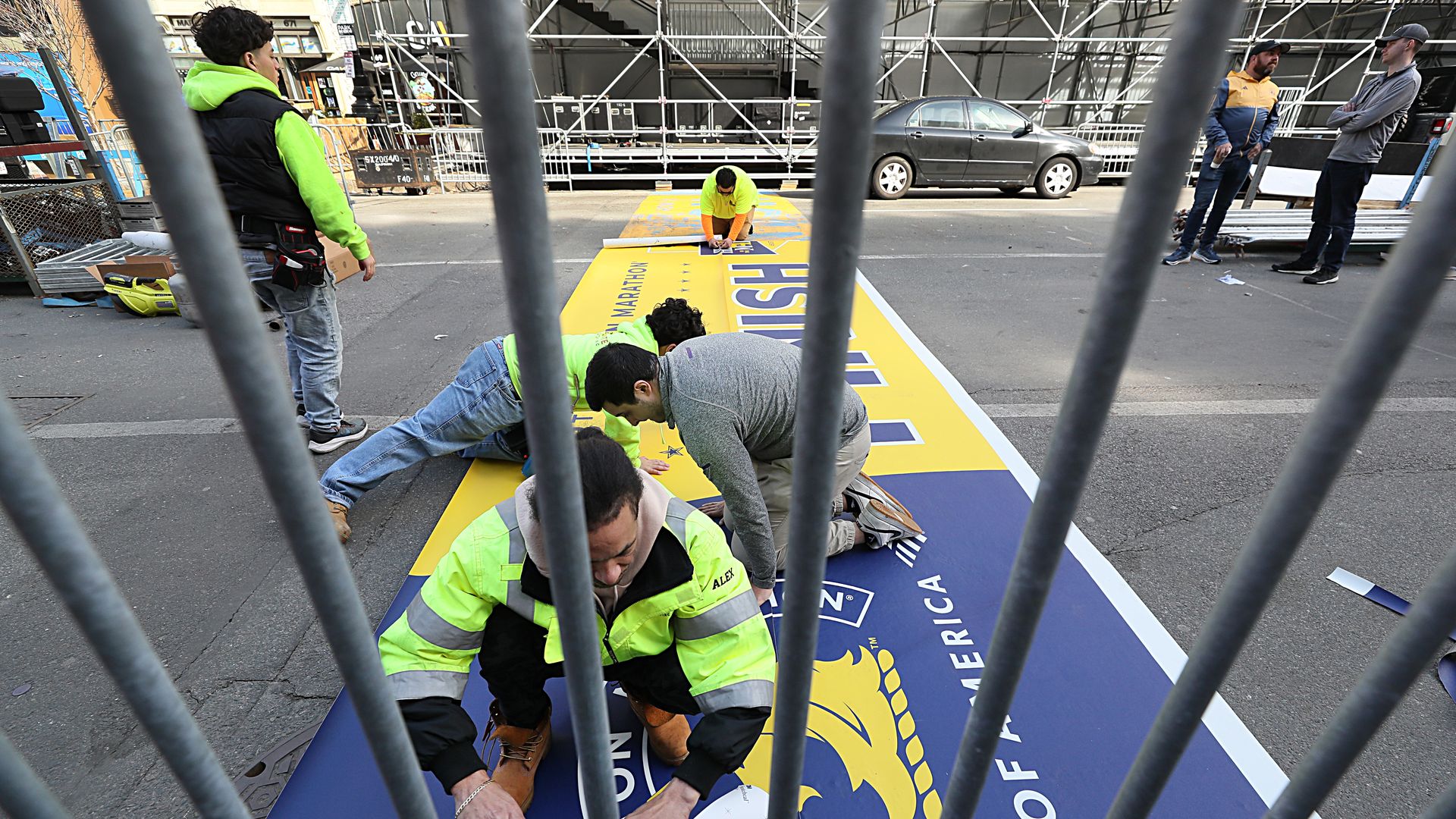 Crews on the ground on Boylston Street work on the finish line of the 2024 Boston Marathon. 