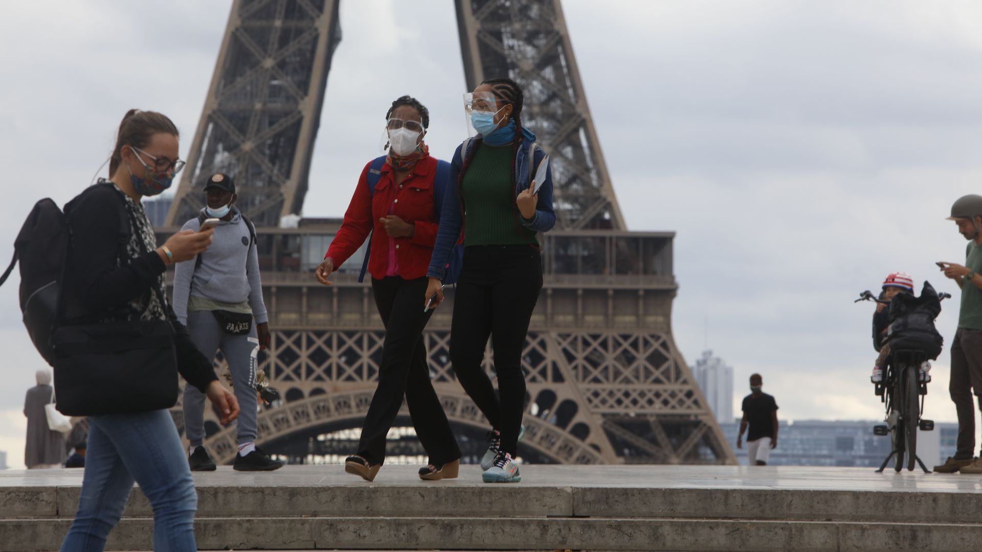 People wearing face masks walk on the Trocadero esplanade, a front the Eiffel Tower in Paris, France