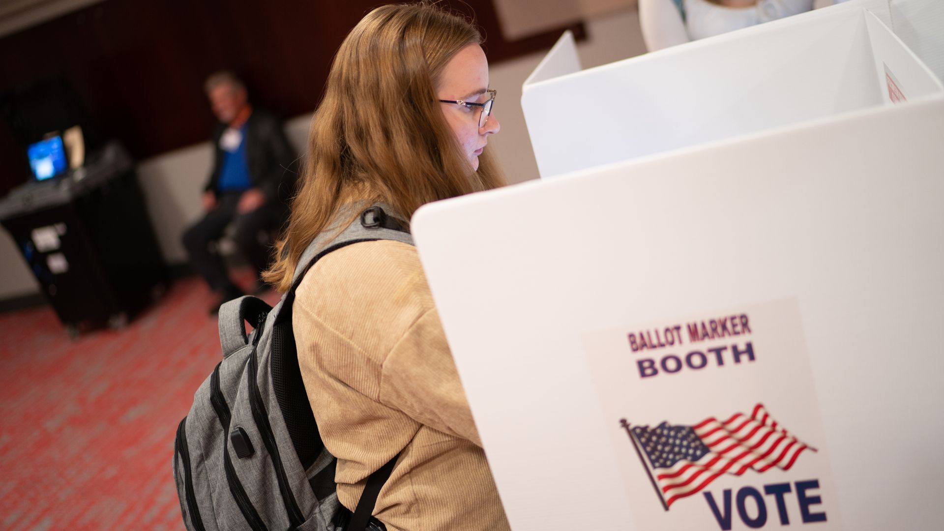 A young woman voting at a polling place.