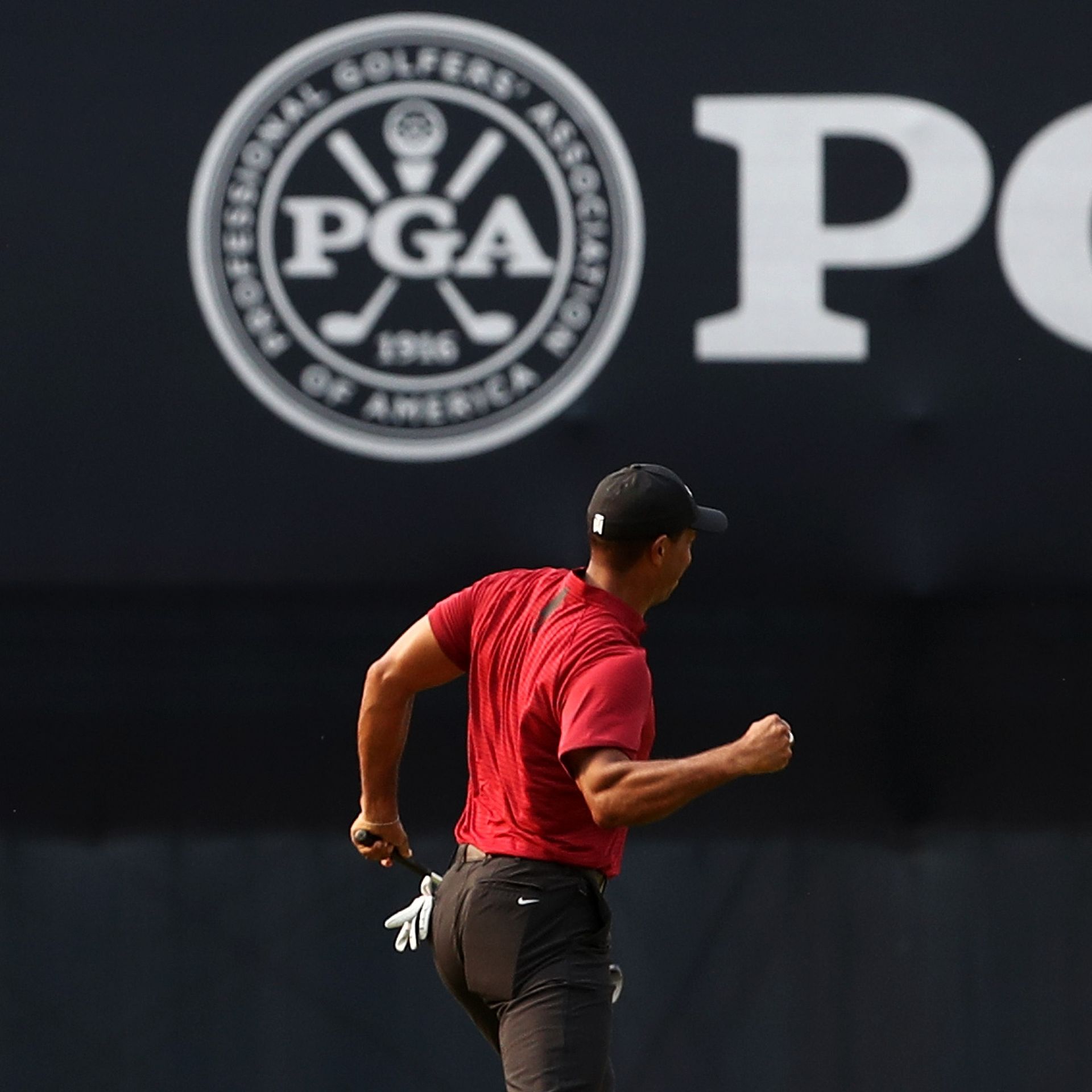 PGA Tour member Tiger Woods celebrates a putt in front of a PGA Tour sign.